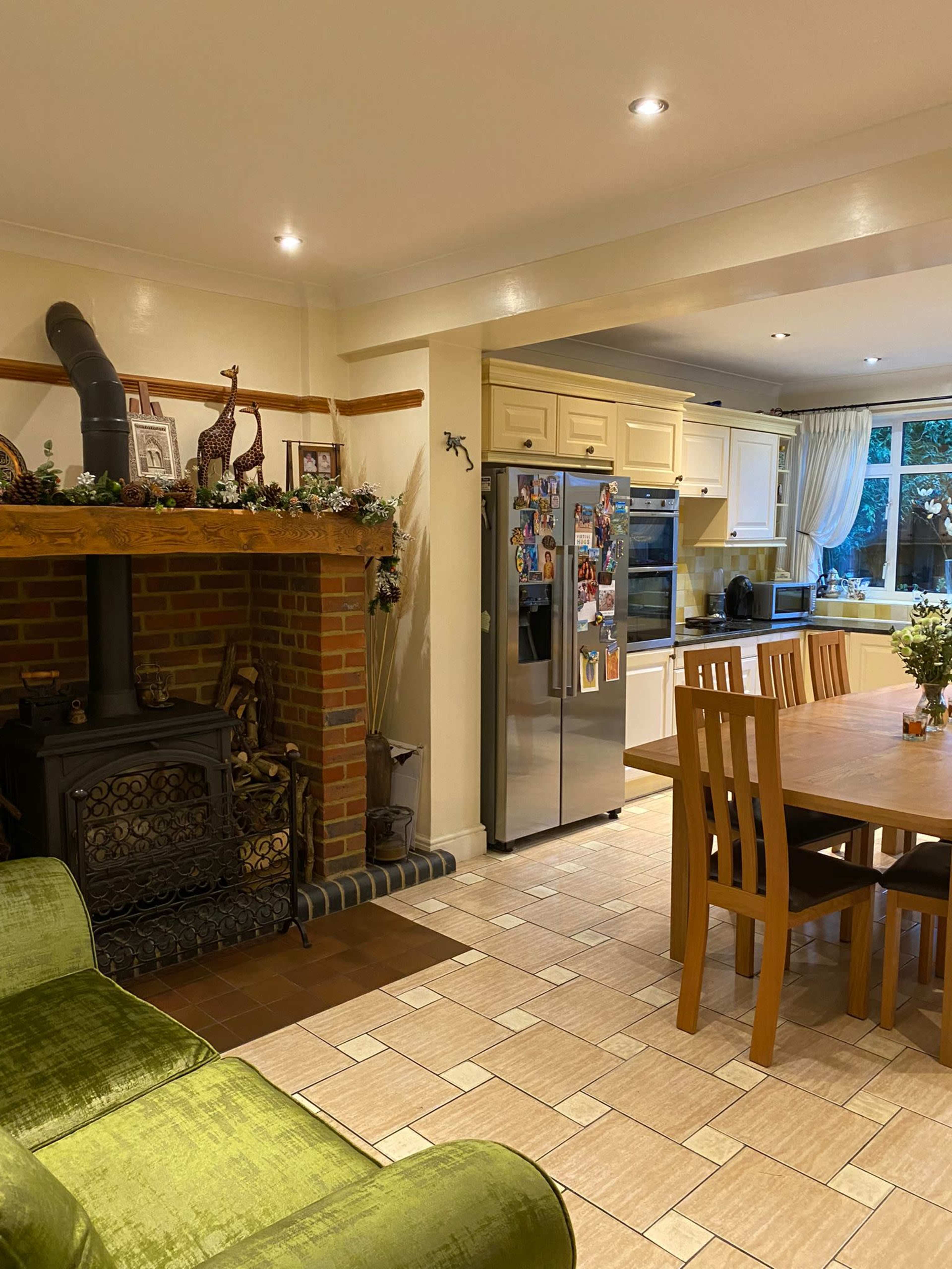 A spacious kitchen area with a dining table, a large refrigerator, and a cozy seating area near a brick fireplace.