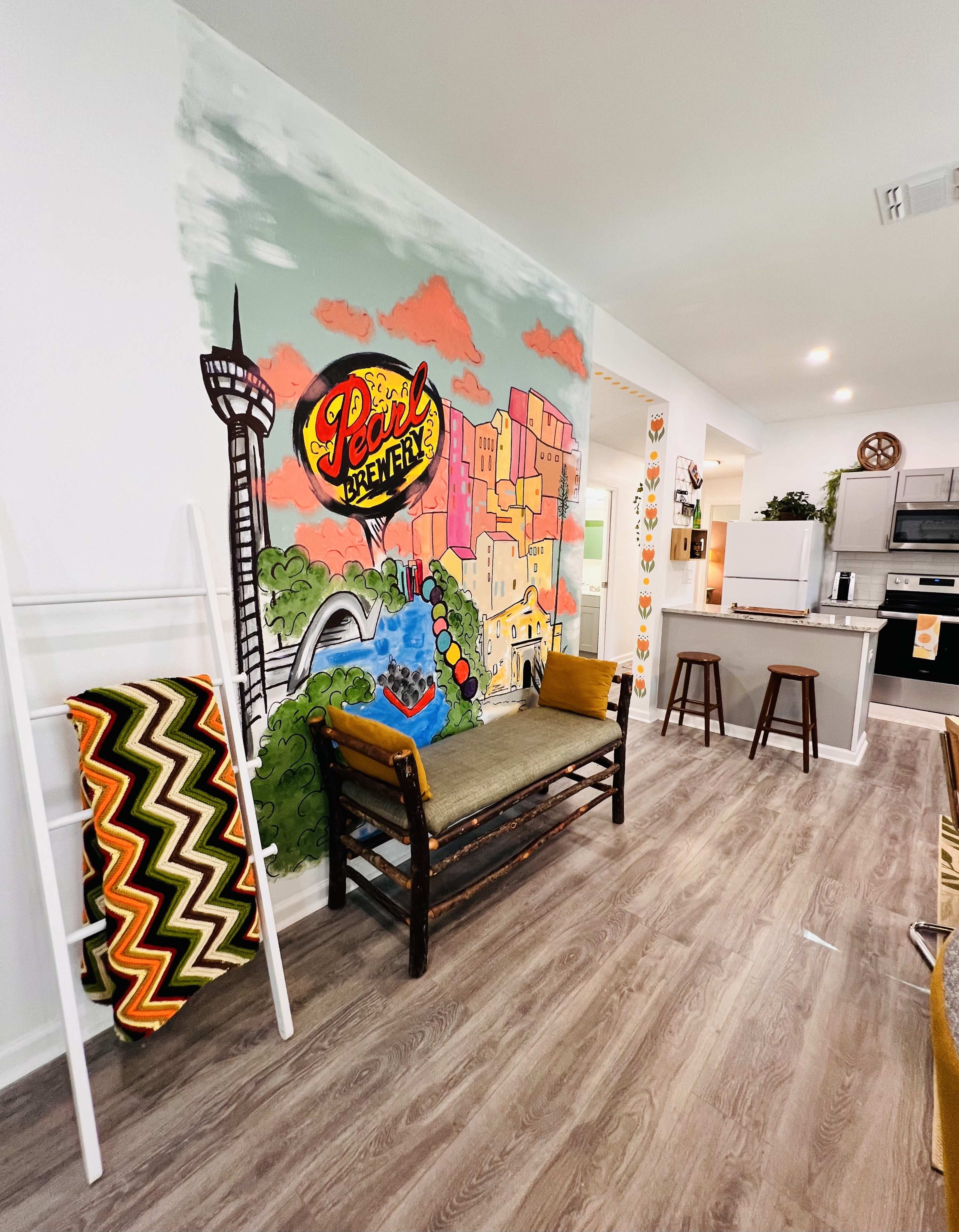 A colorful mural on a wall featuring a cityscape, with a wooden bench and decorative items in a modern living area.