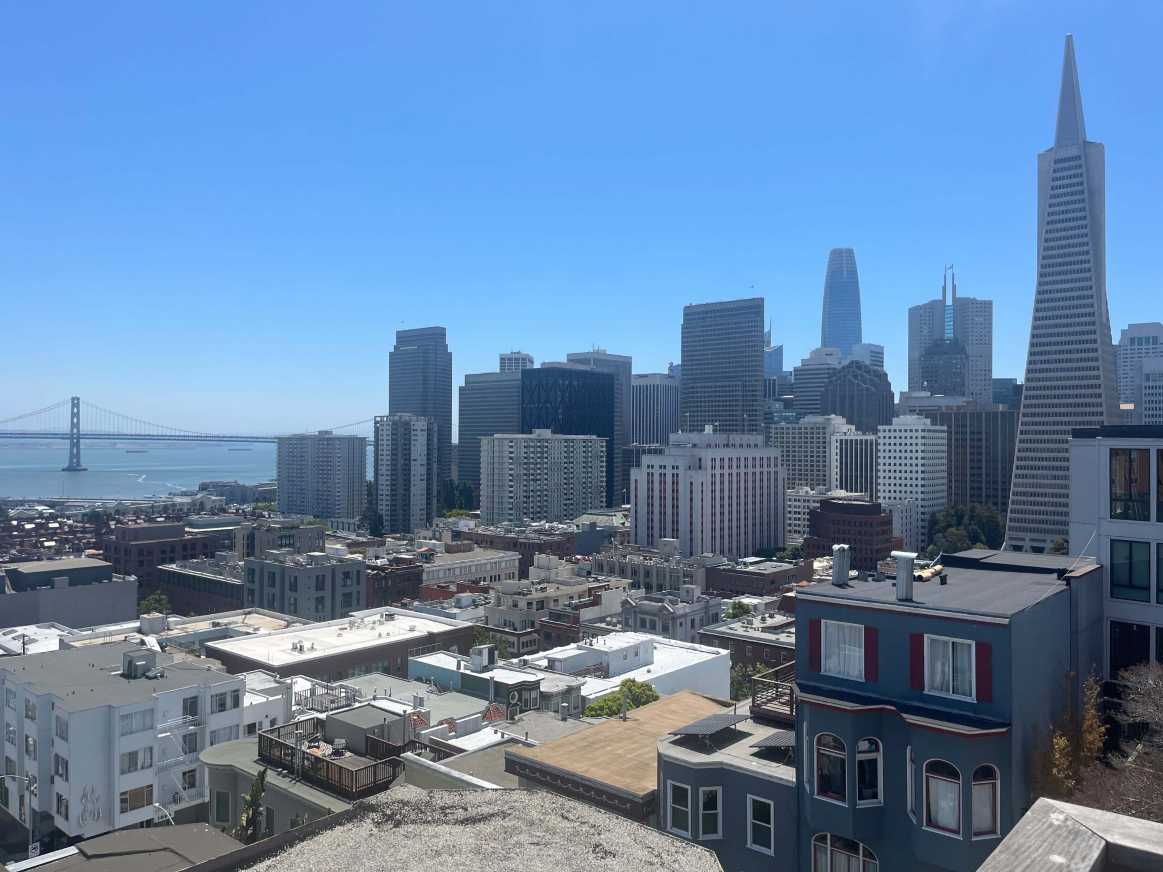 A view of San Francisco's skyline with various tall buildings and the Bay Bridge in the background.