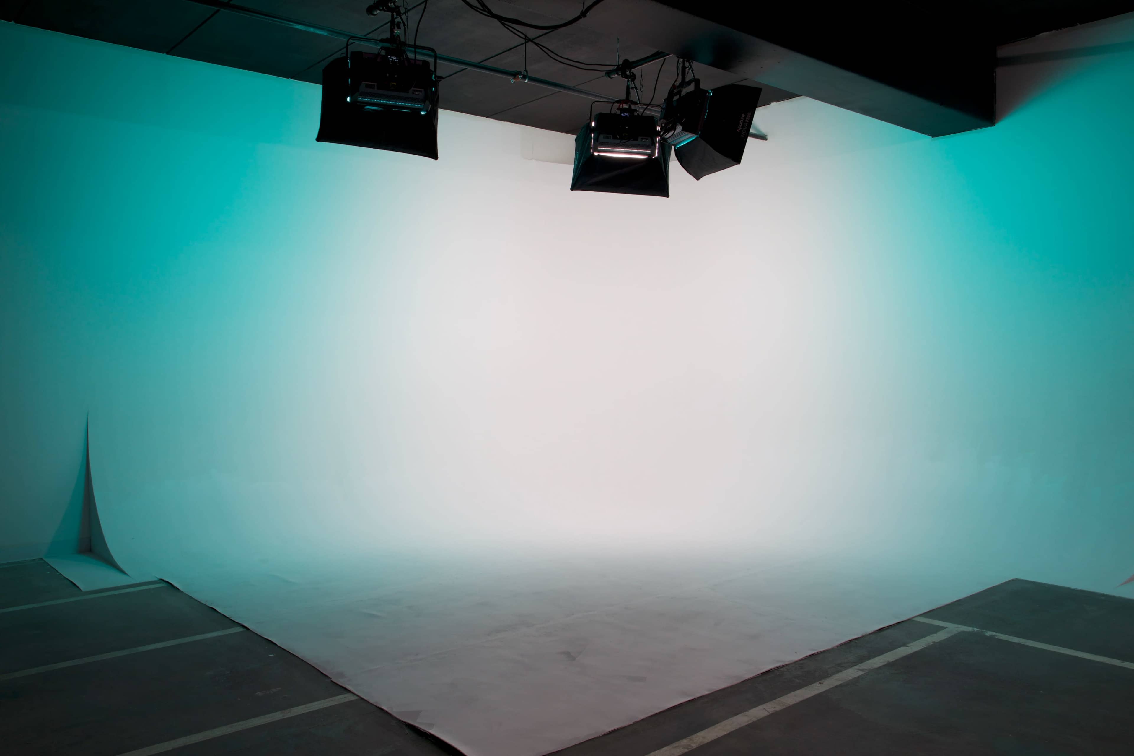 A minimalistic photography studio with a seamless backdrop and studio lights mounted on the ceiling.
