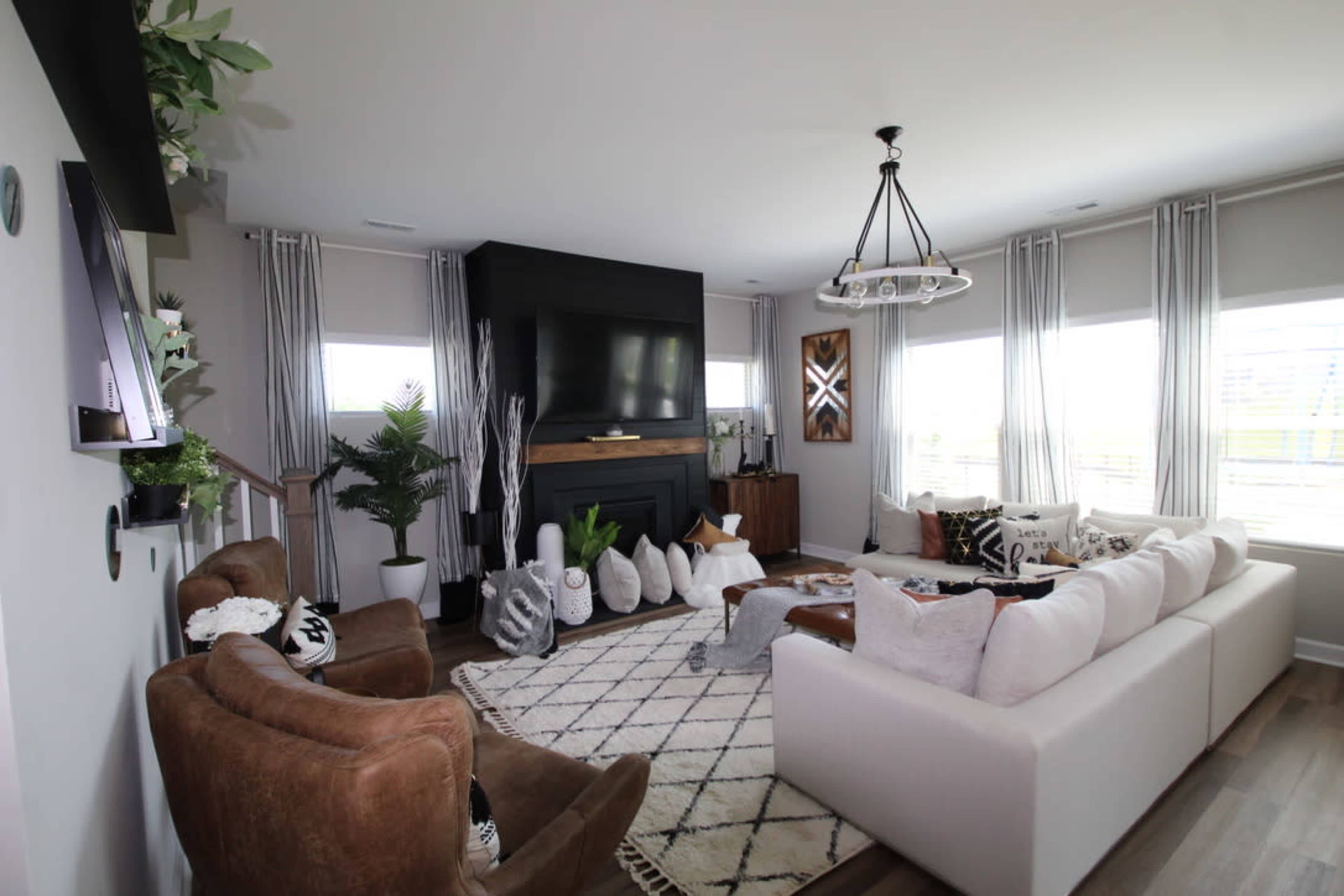 The living room features a large white couch, a brown armchair, a modern fireplace, and large windows allowing natural light to fill the space.