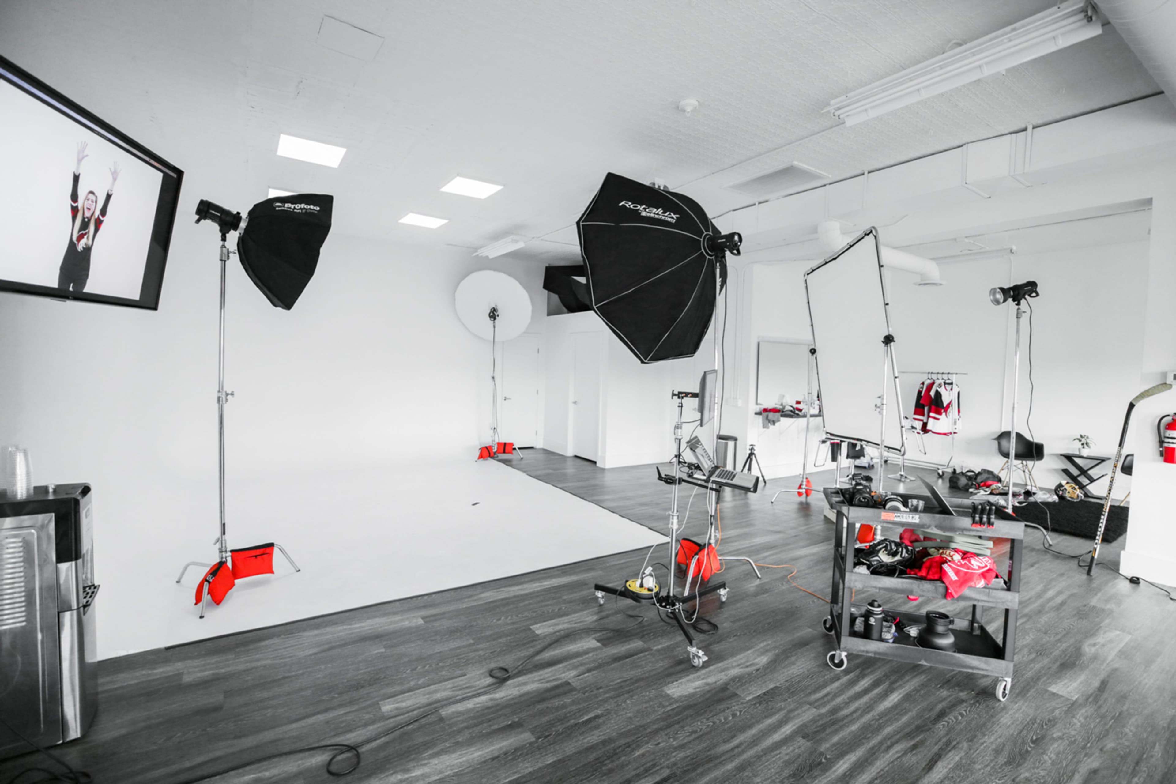 A photography studio is set up with multiple lighting equipment, a backdrop, and various props organized on a cart.
