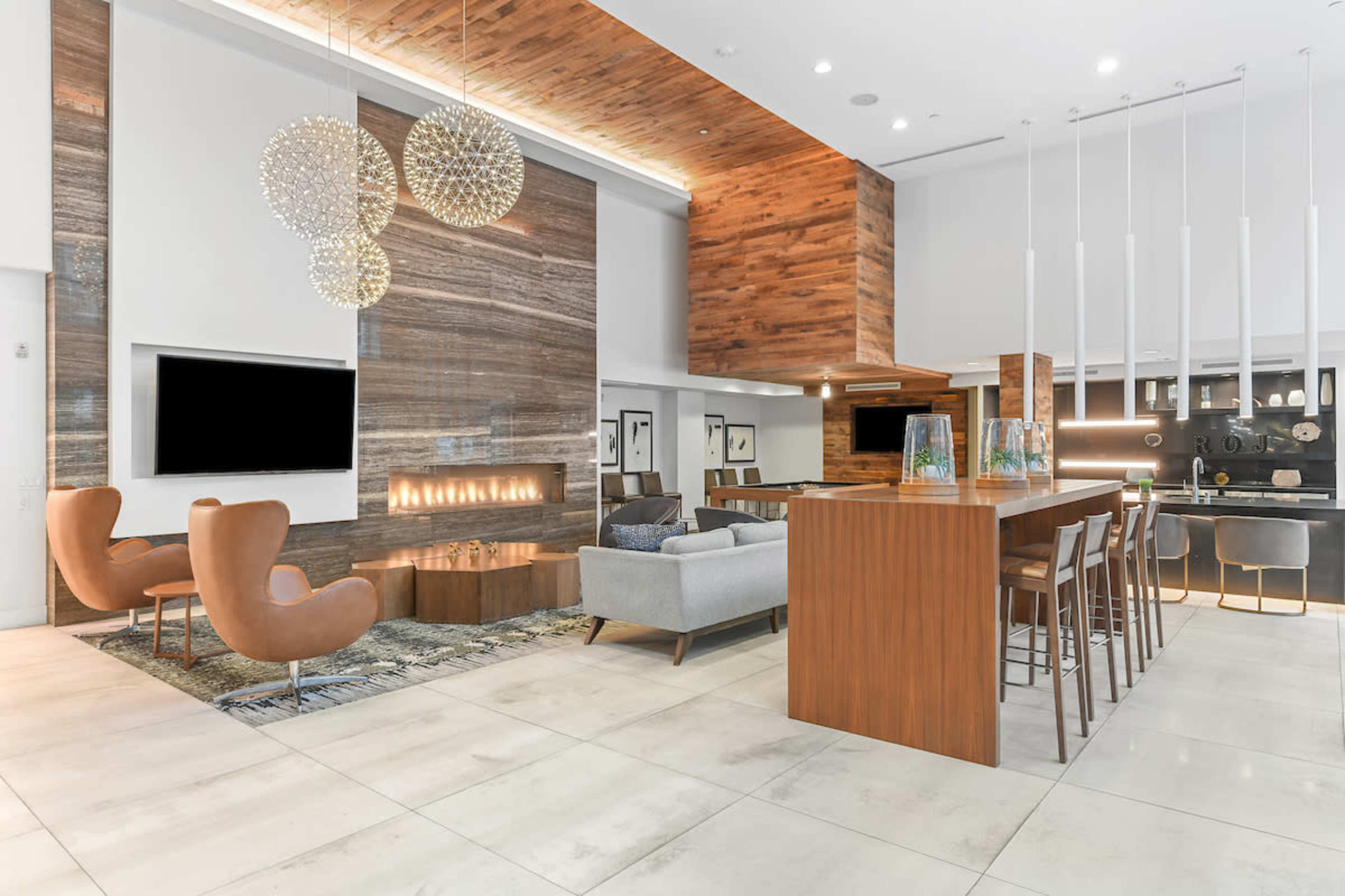 A modern lounge area with a fireplace, comfortable seating, and a bar counter in a spacious interior.