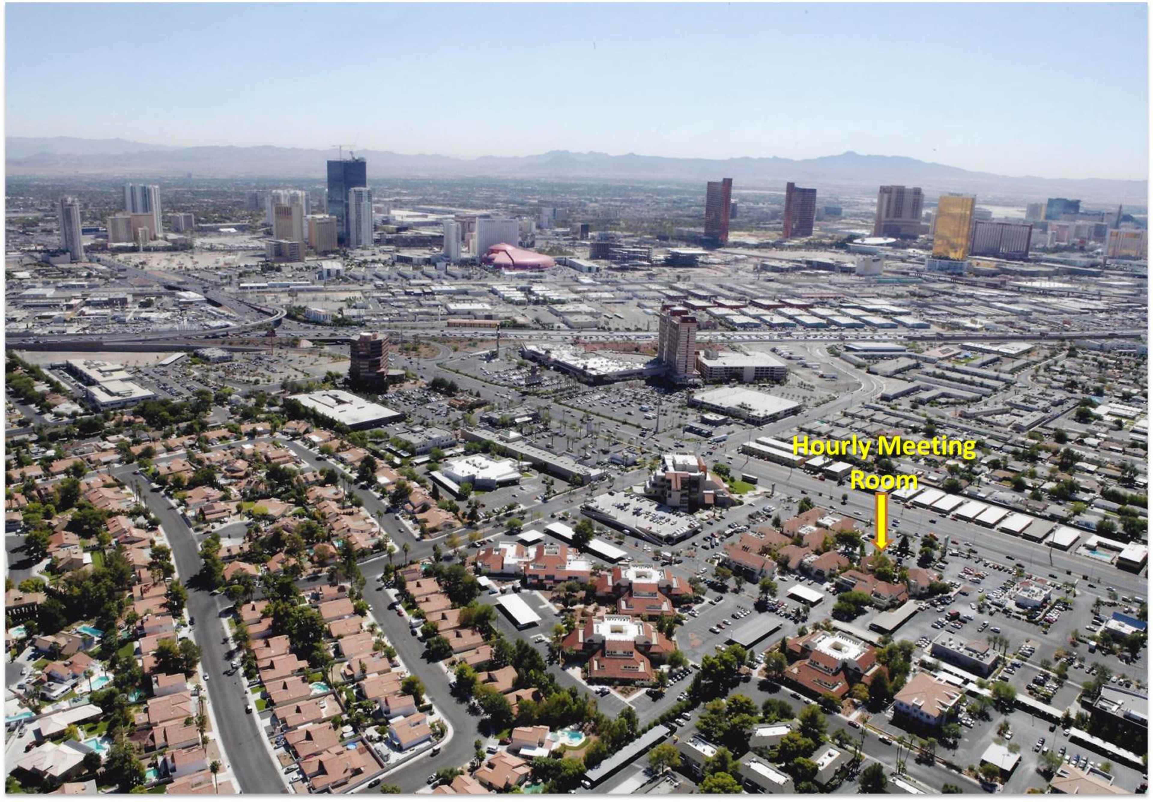 An aerial view of a section of Las Vegas shows residential areas in the foreground and several hotels and casinos in the background.