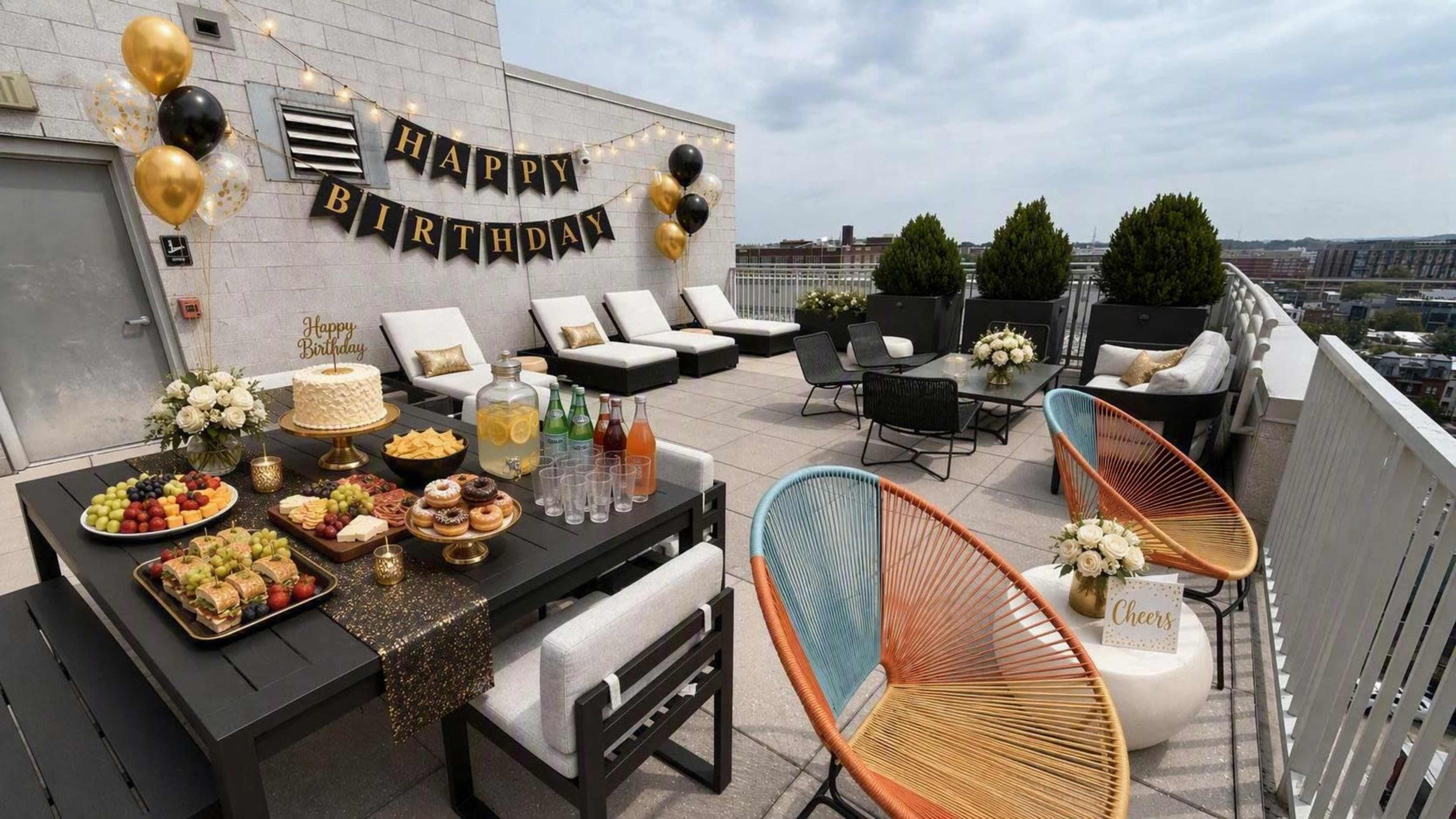 A rooftop party setup features a "Happy Birthday" banner, decorated tables with food and drinks, and comfortable seating arrangements.