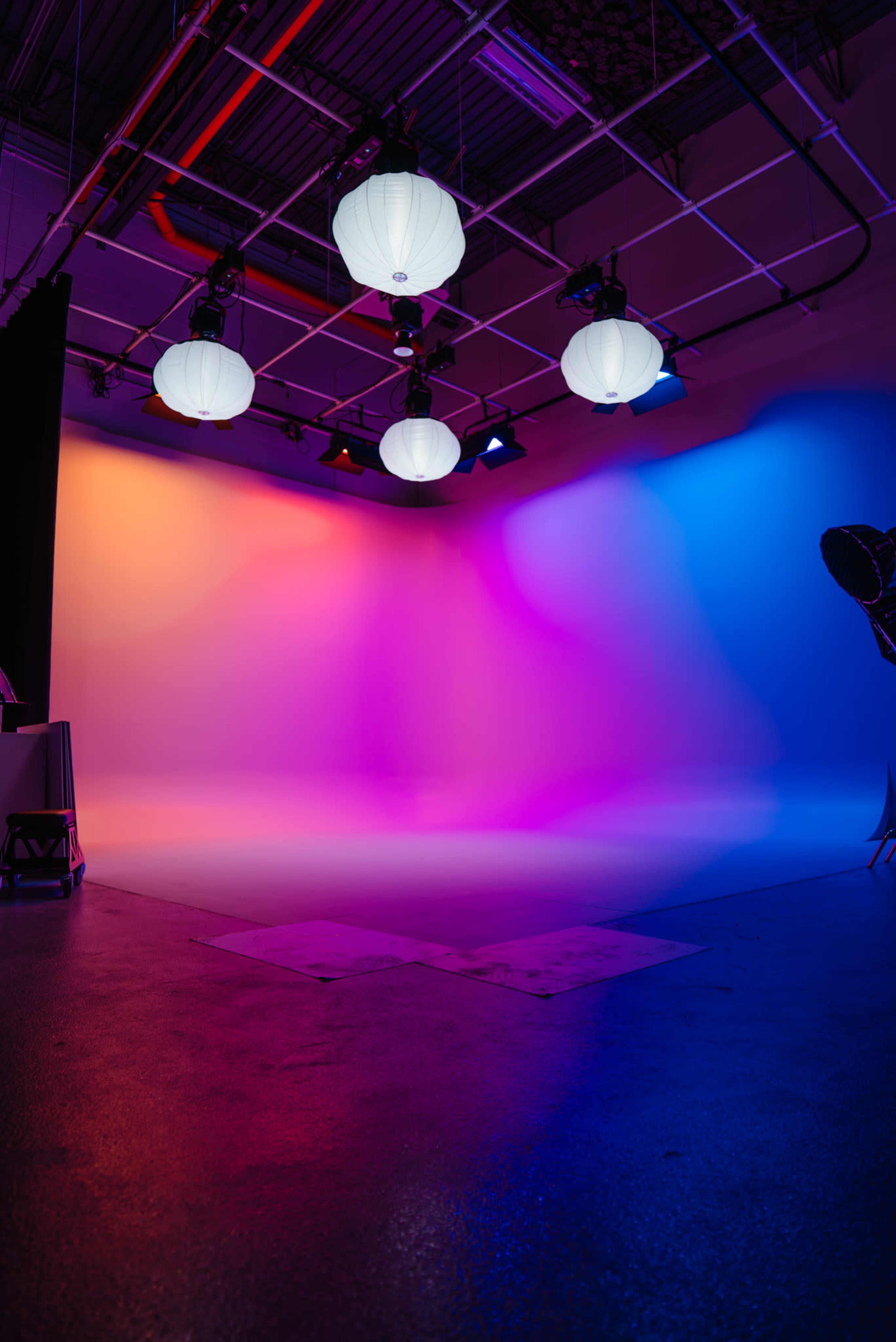 The image shows a studio space with colorful, gradient lighting and several hanging paper lanterns.