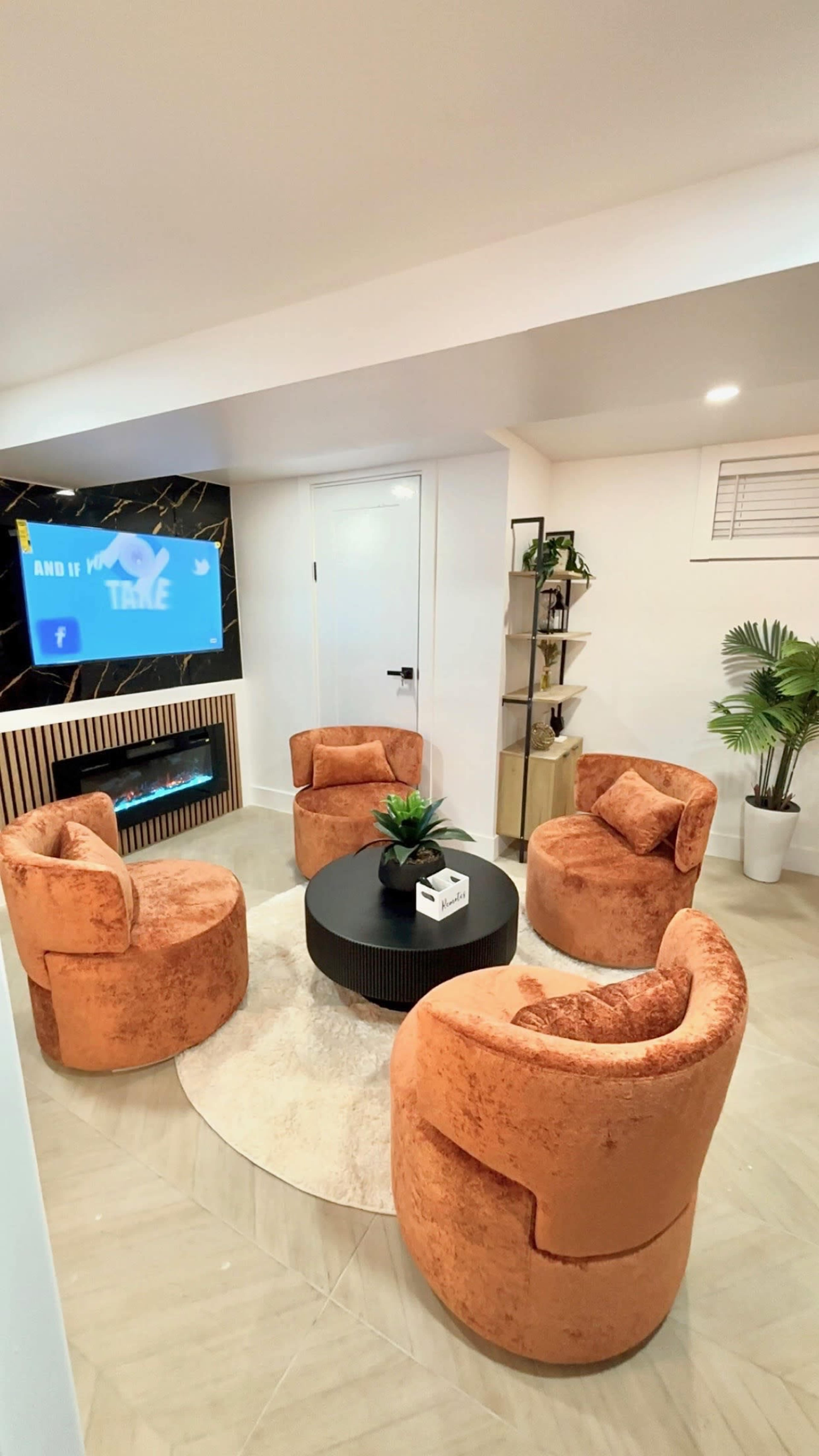 The image shows a cozy seating area featuring four round, upholstered chairs arranged around a circular black coffee table on a light-colored floor.