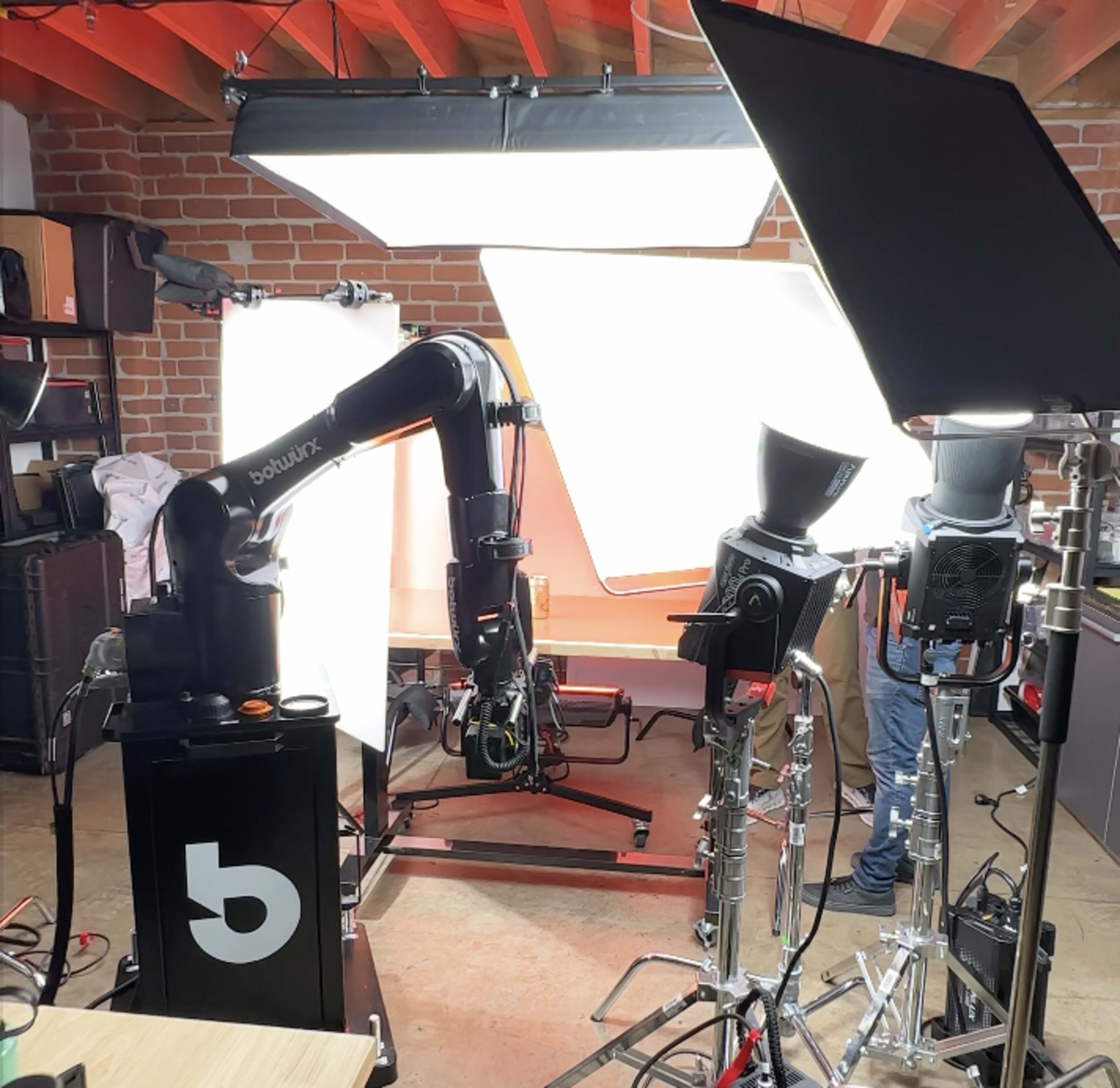 A photography studio equipped with lighting equipment, a robotic arm, and various cameras set up for a shoot.