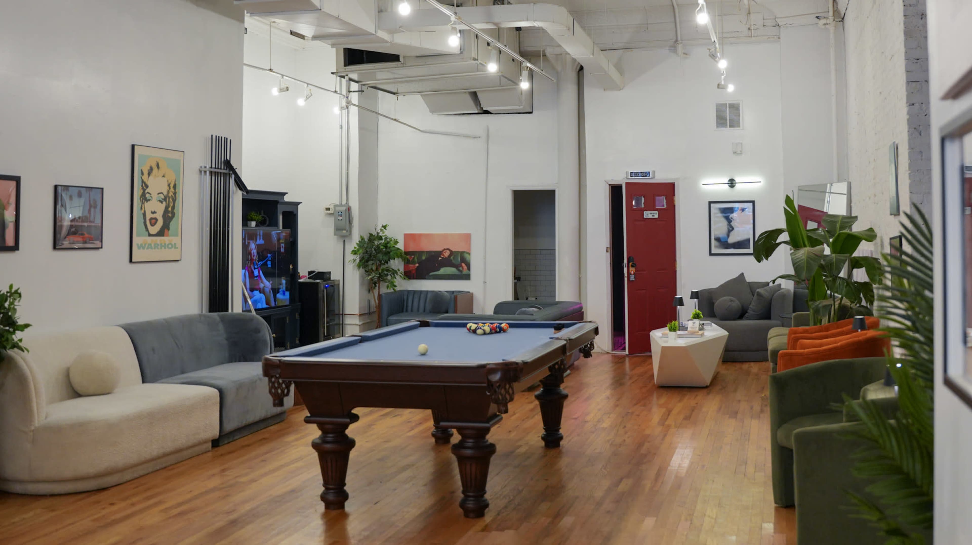 The image shows a spacious lounge area featuring a pool table, various seating arrangements, and decorative wall art.