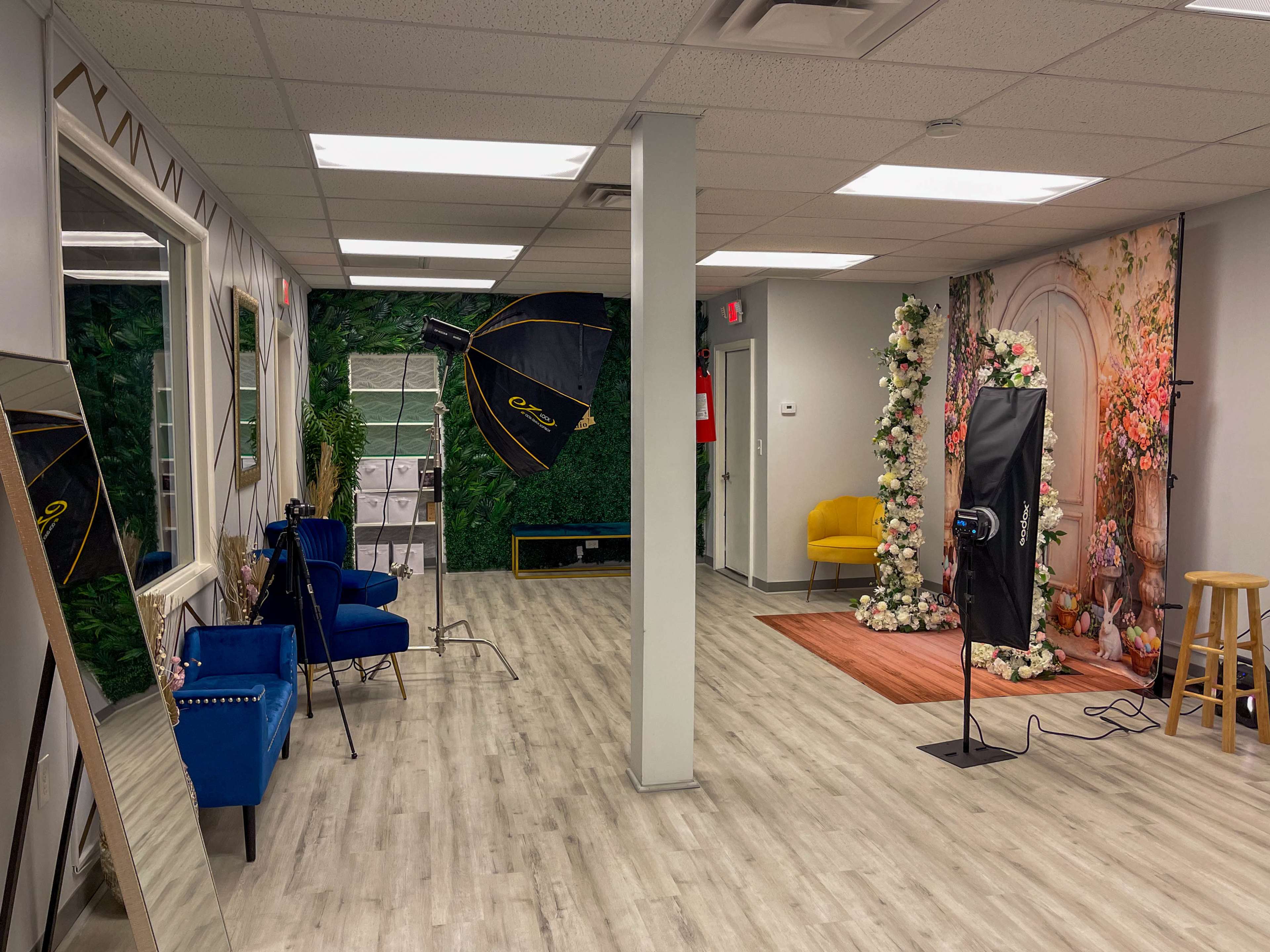 A photography studio with a flower-decorated backdrop, lighting equipment, and various seating arrangements.