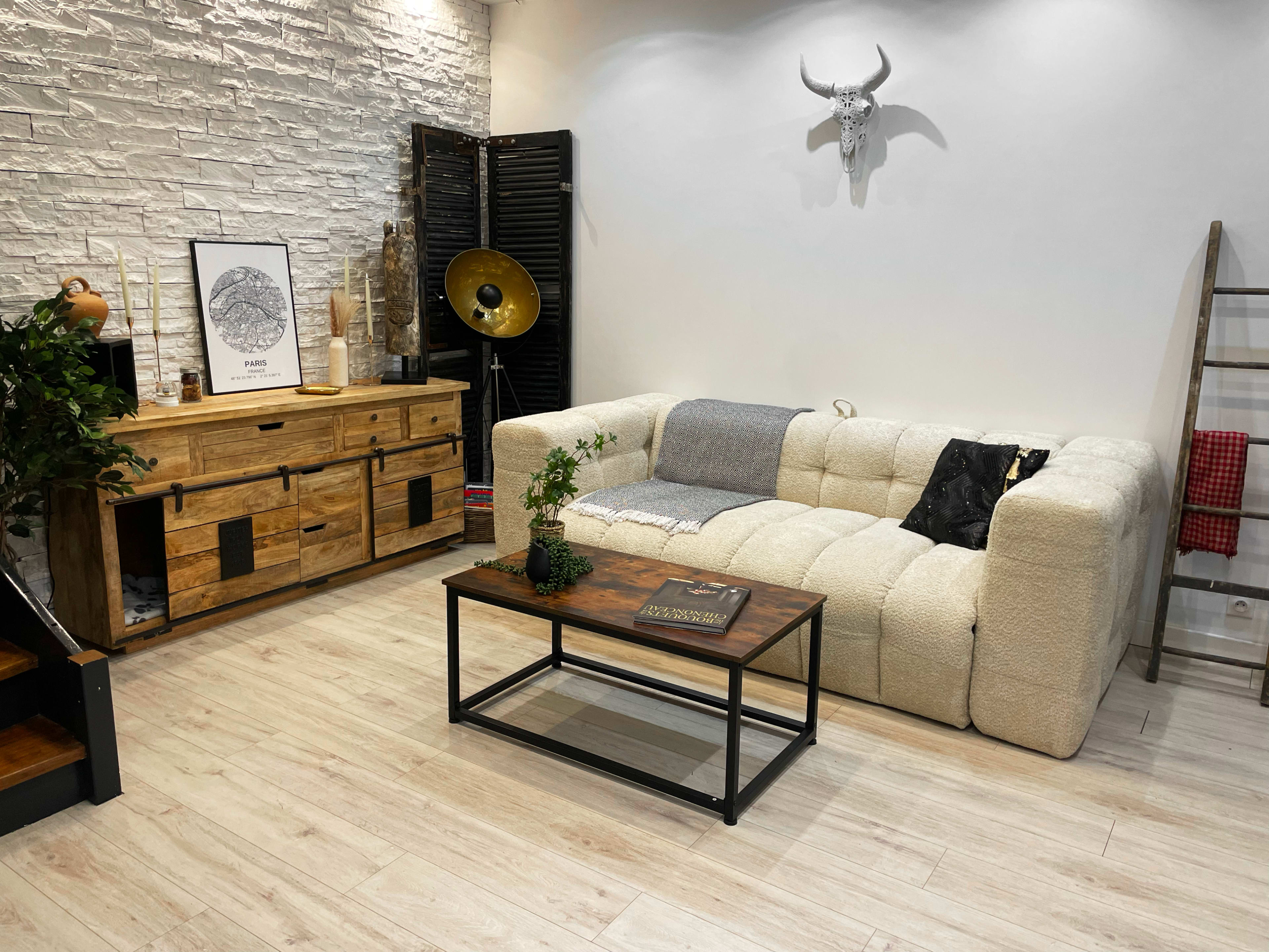 A spacious living area features a light-colored, textured sofa, a wooden coffee table, and a decorative console against a white brick wall.