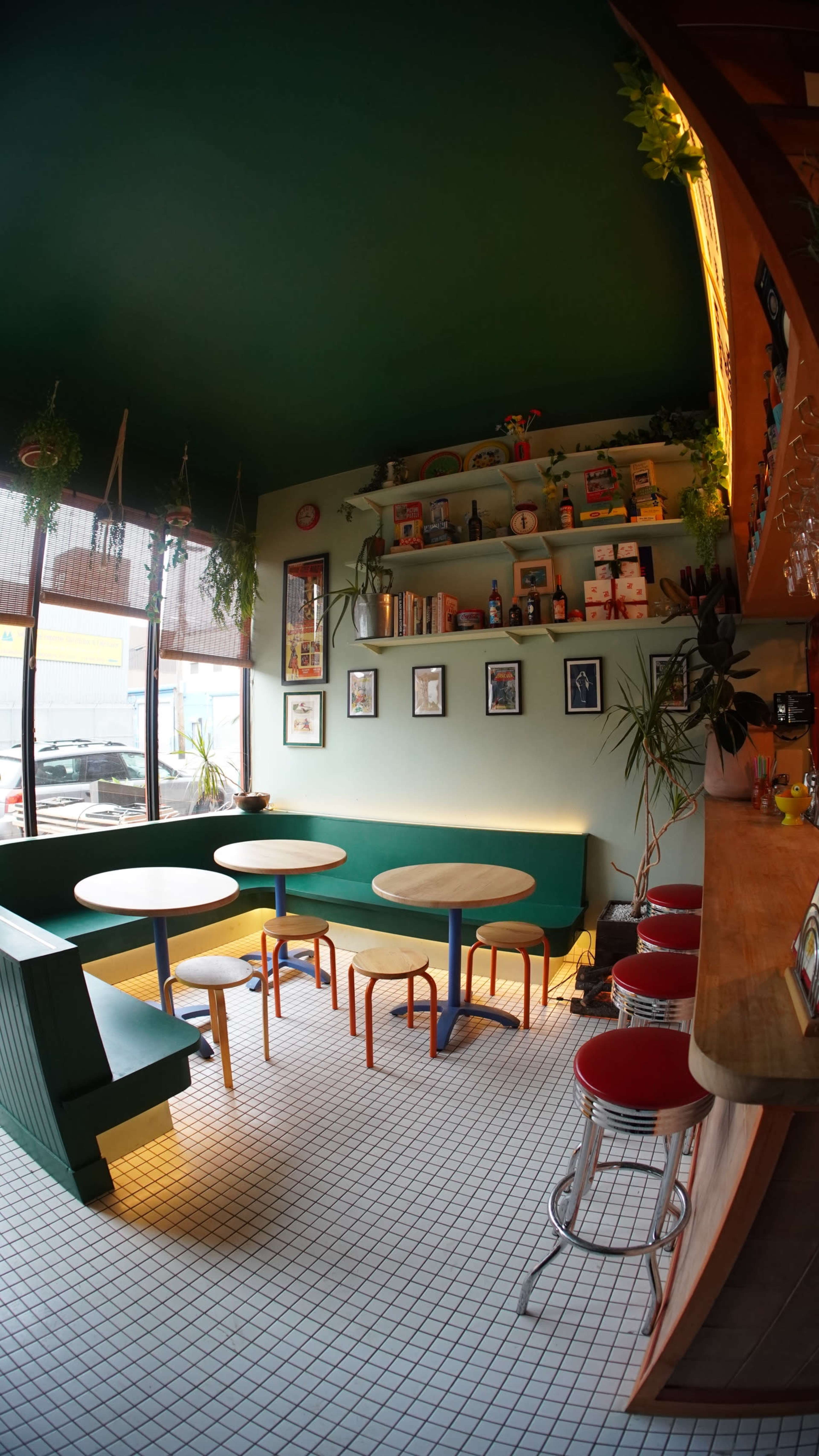 A cozy café features colorful seating and shelves adorned with books and decor, illuminated by warm lighting.