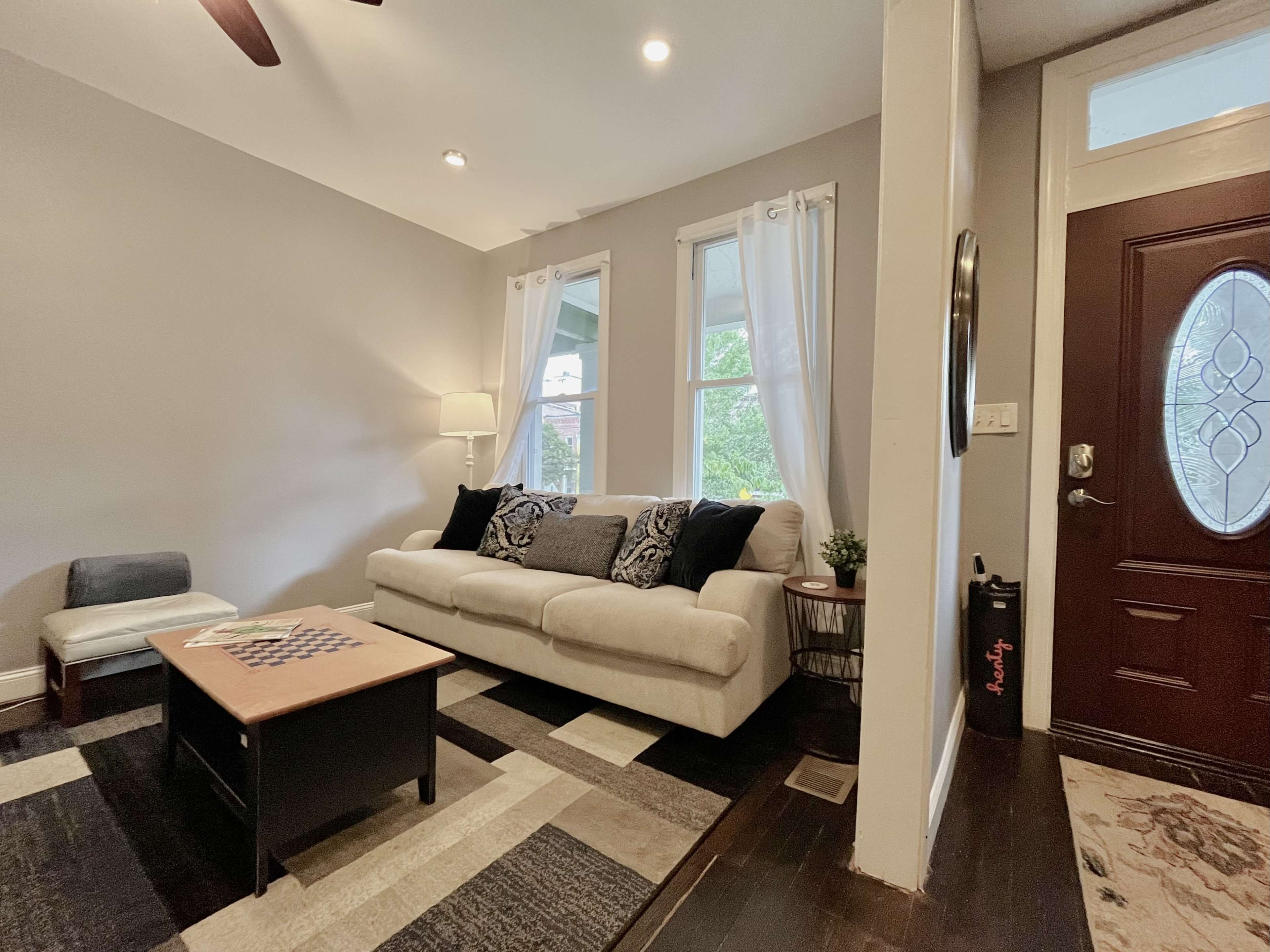 A living room with a light-colored sofa, a coffee table, and large windows letting in natural light.