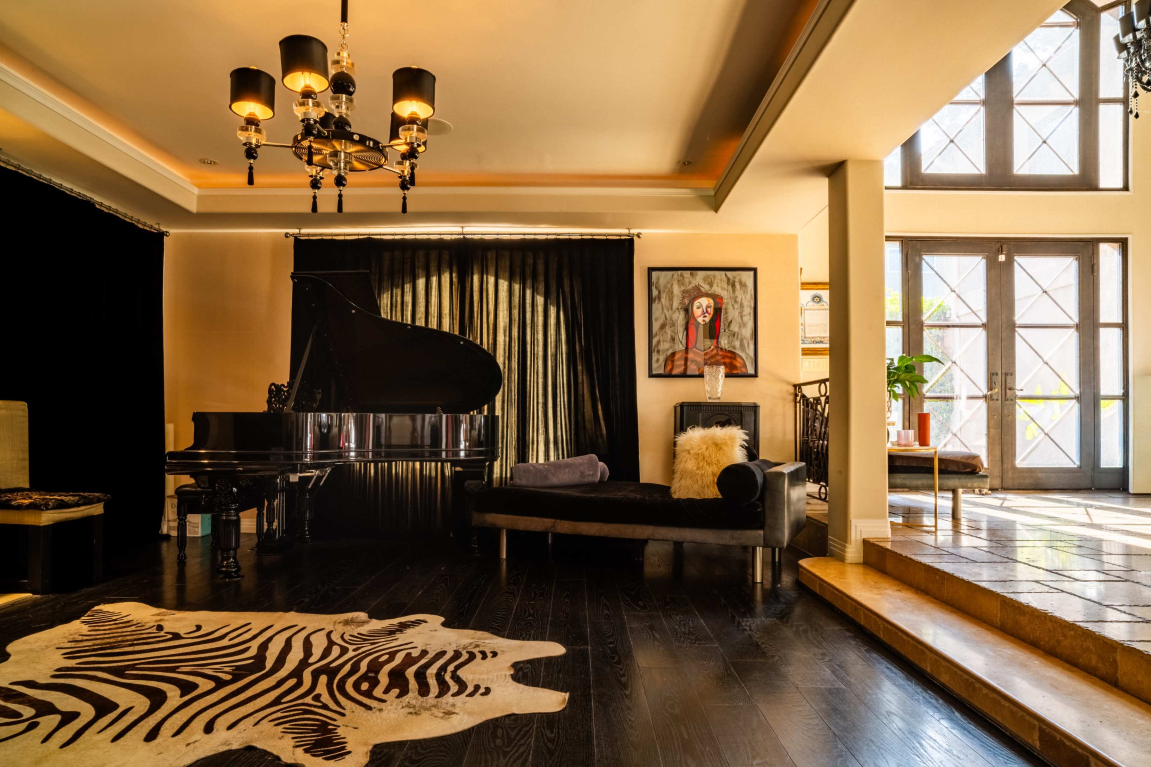 The image depicts a living room featuring a grand piano, a black sofa, a zebra-patterned rug, and large windows illuminated by natural light.