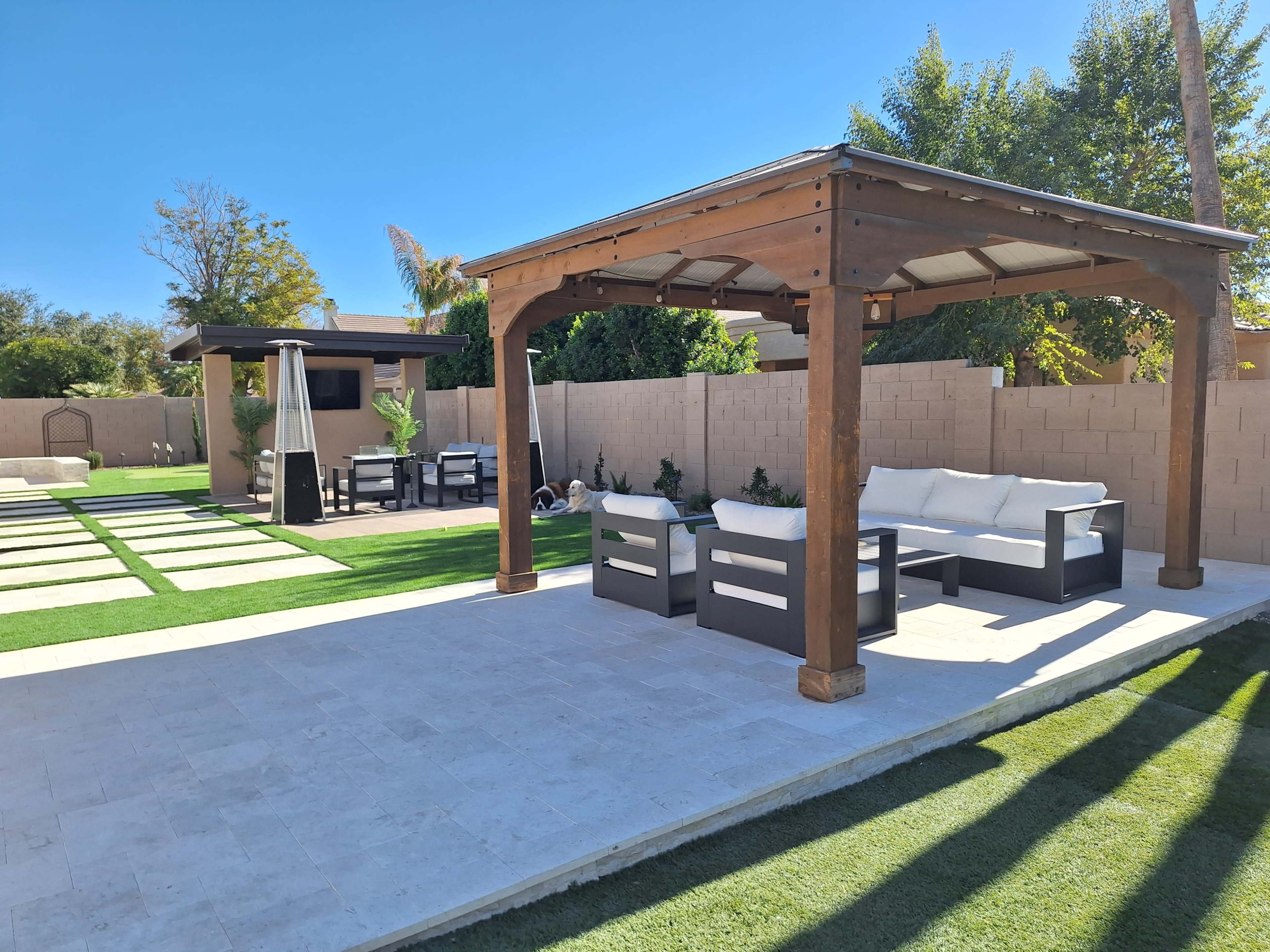 The image shows a landscaped backyard featuring a wooden gazebo with seating, a stone patio, and manicured grass areas.