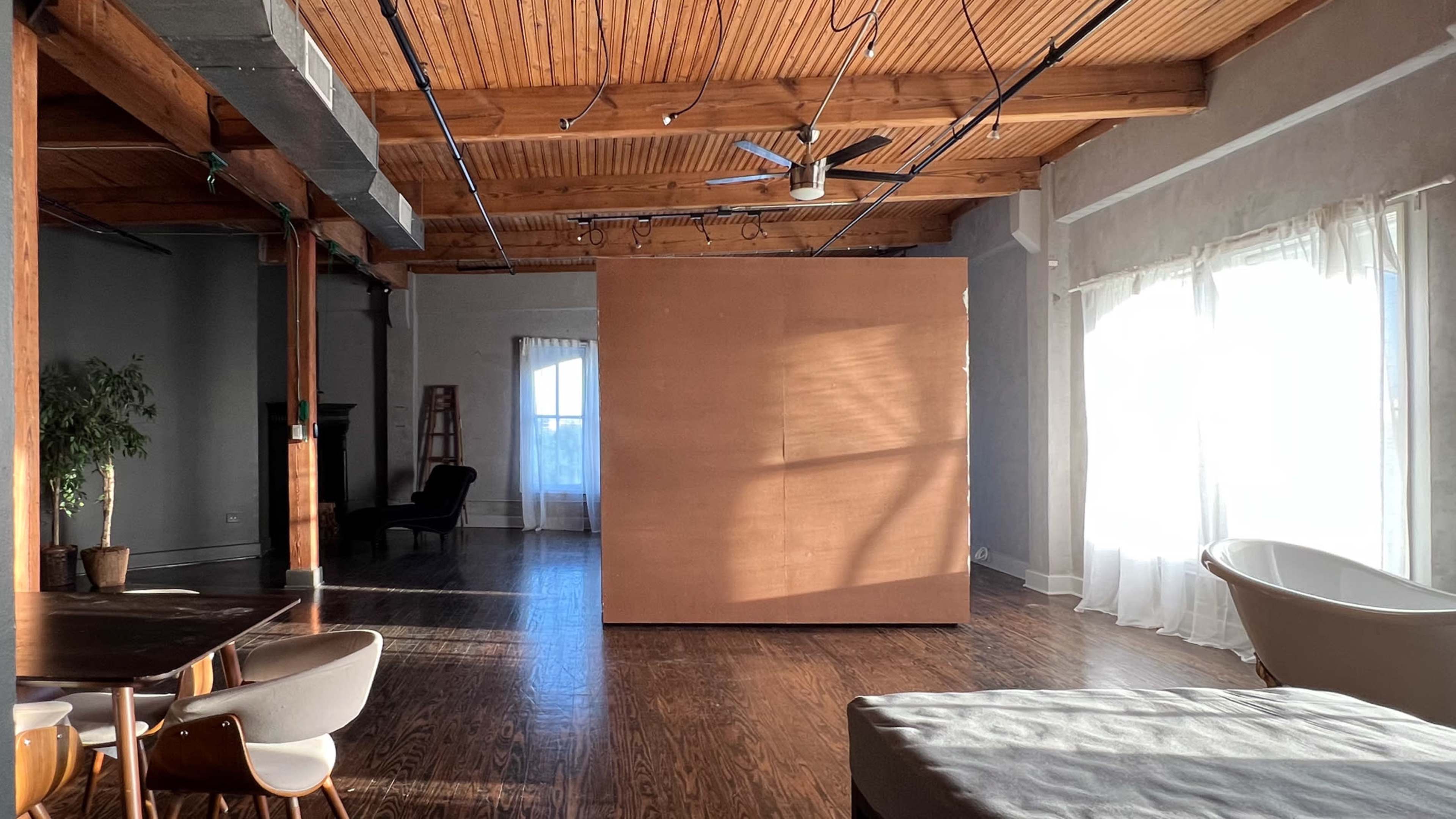 A spacious room with wooden beams, large windows, and a wooden partition in the center.