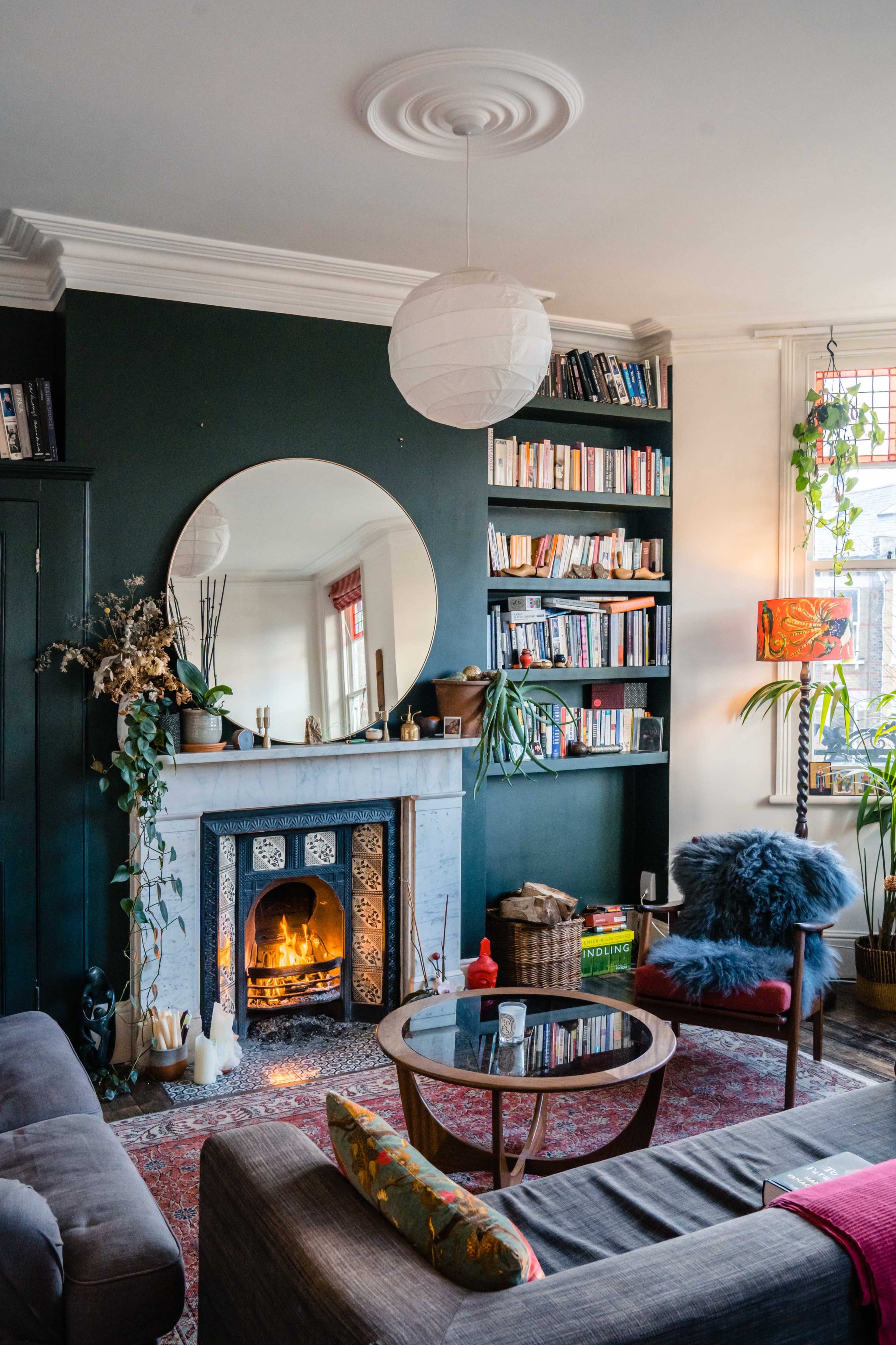 A cozy living room with a marble fireplace, bookshelves filled with books, and a coffee table surrounded by comfortable seating.