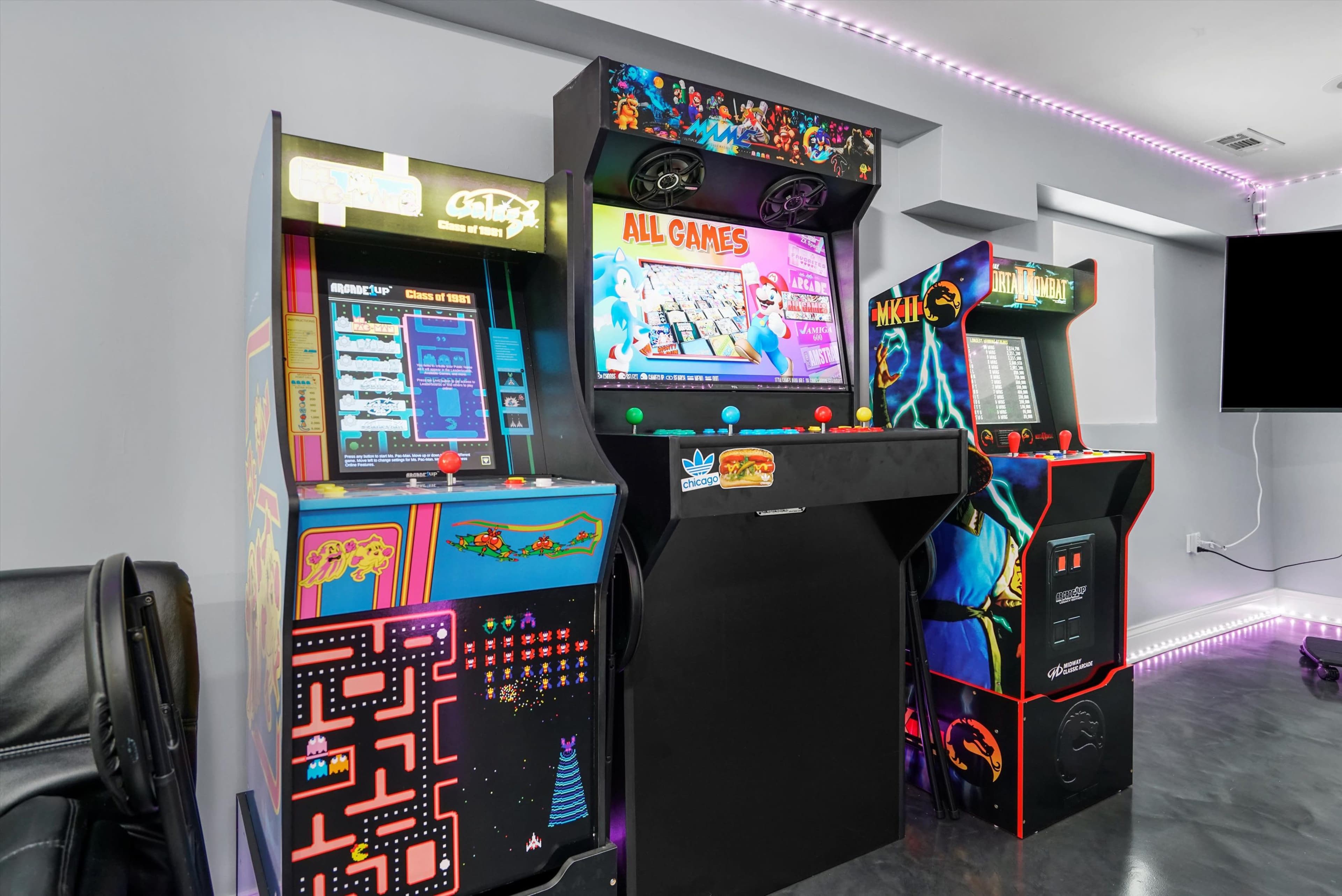 The image shows three retro arcade game machines lined up against a wall, featuring colorful screens and stylized artwork.