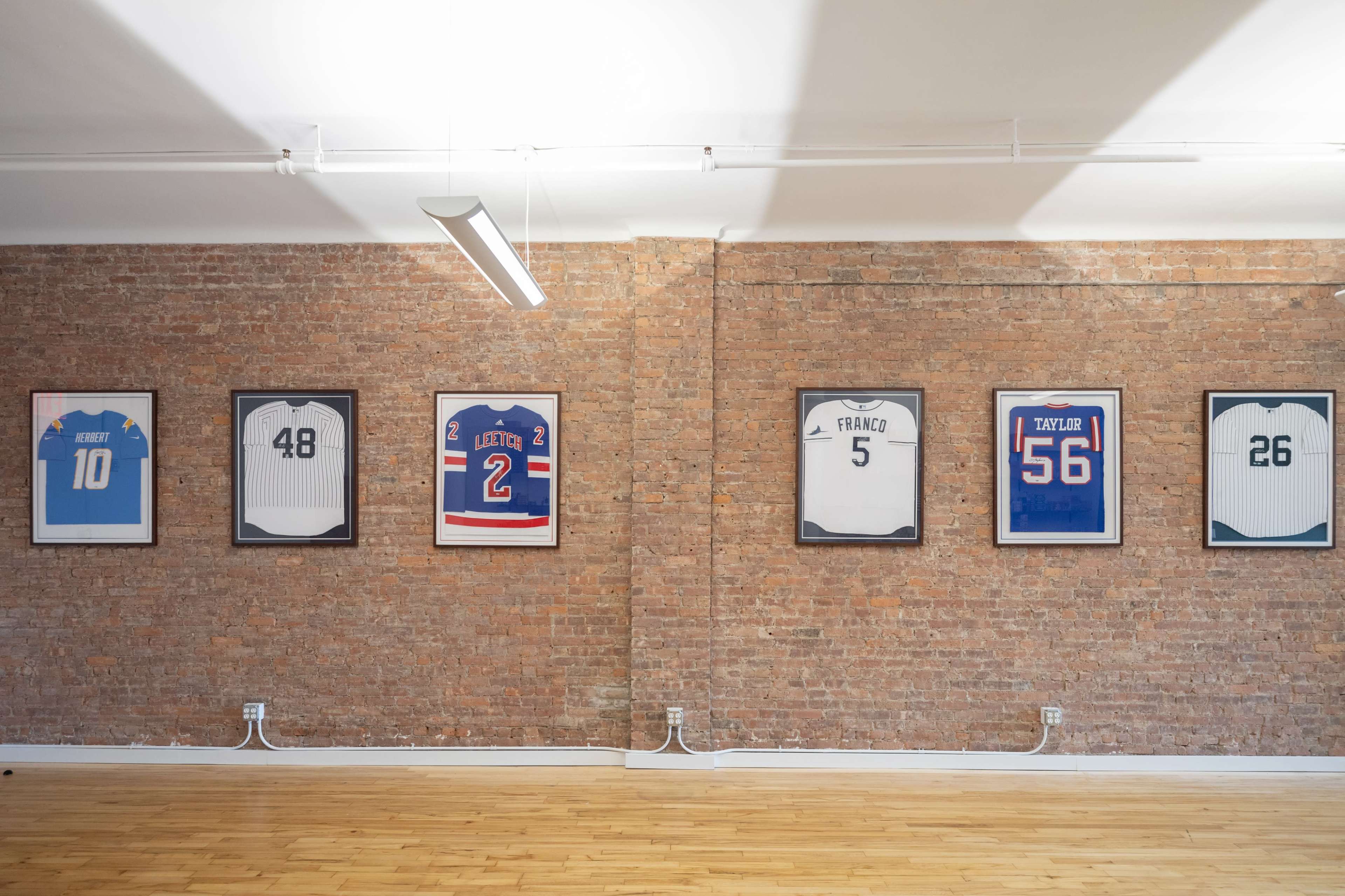 A brick wall adorned with framed sports jerseys, each displaying a different number and name.