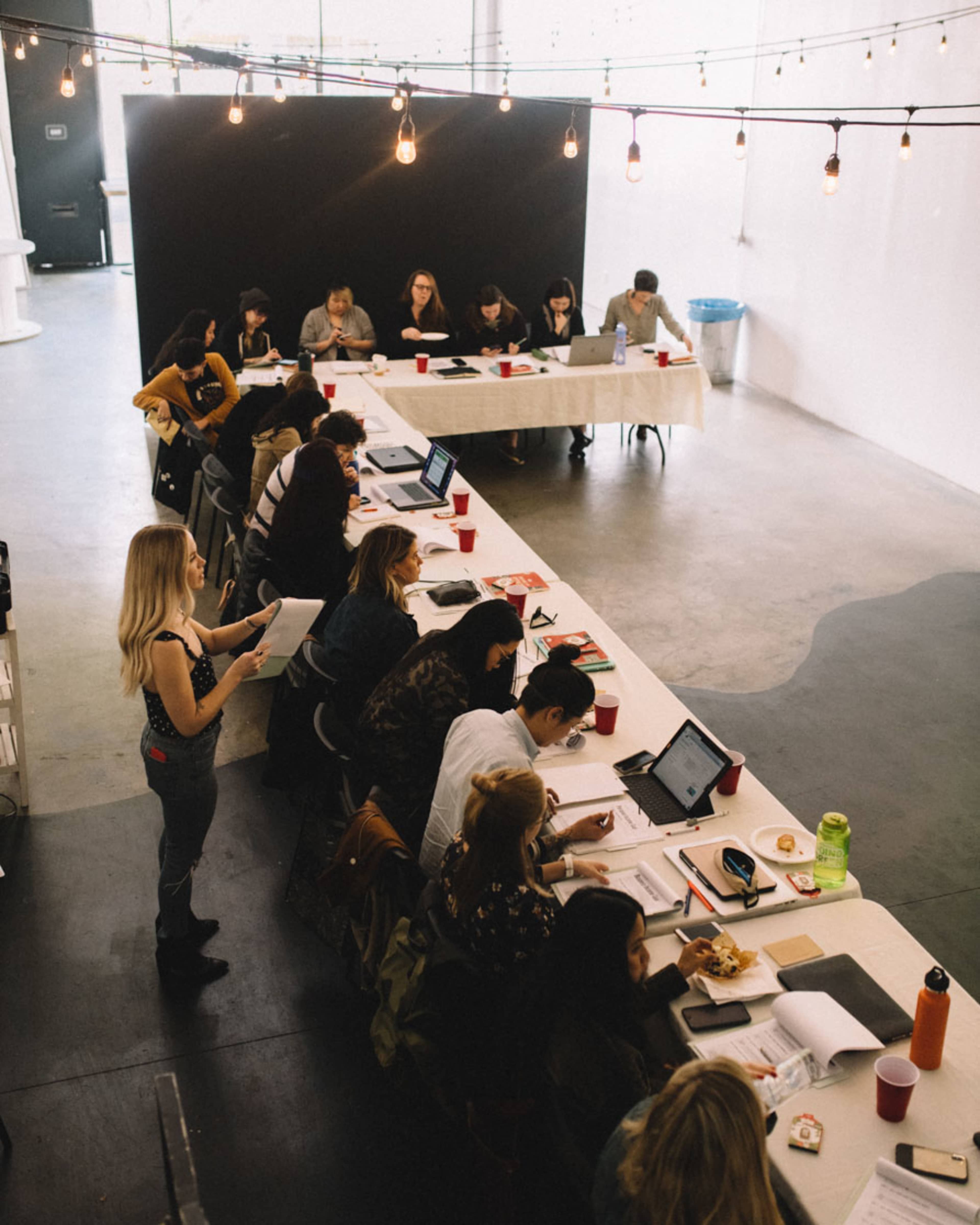 A group of people is studying and working at tables in a well-lit, modern room.