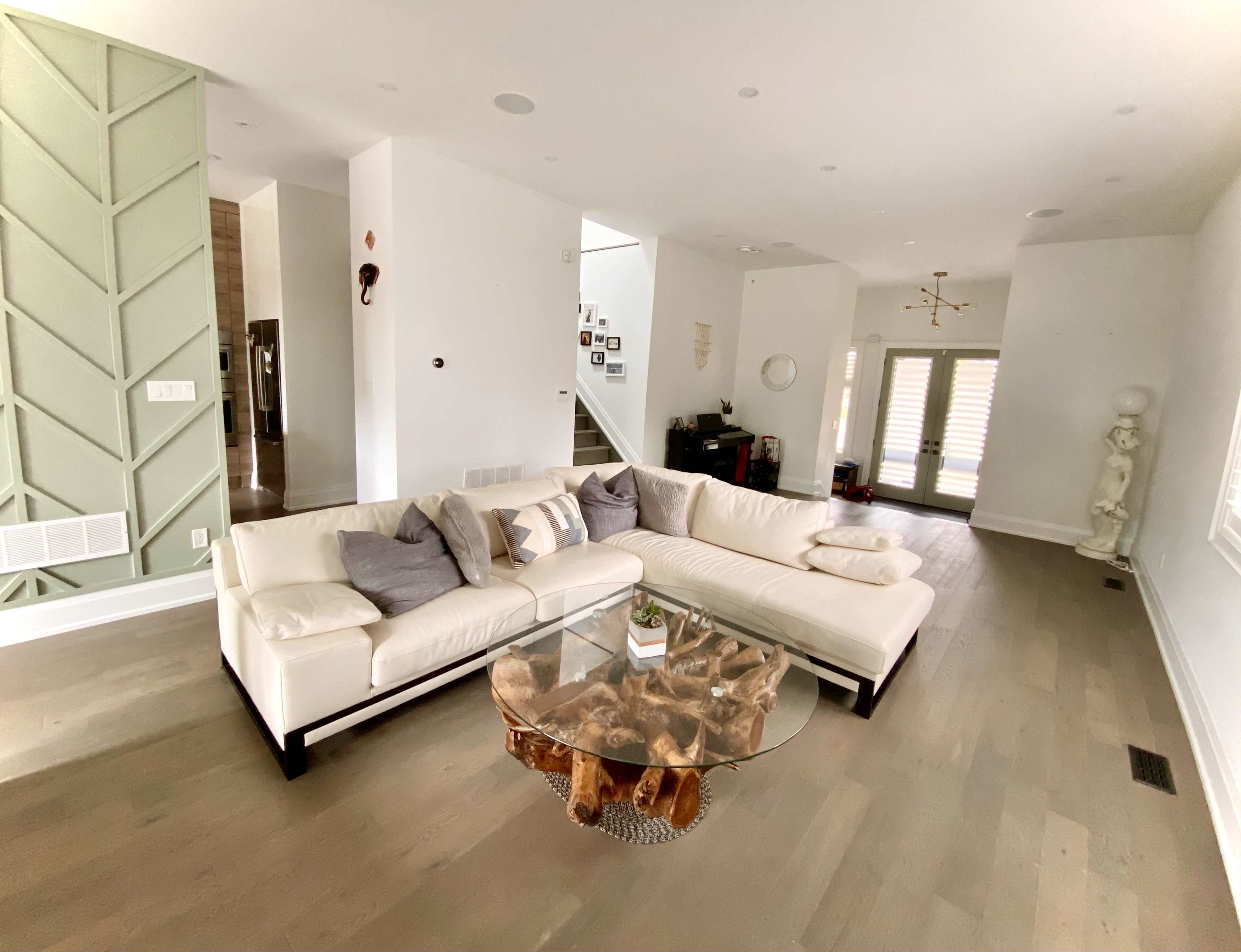 A modern living room featuring a large white sectional sofa, a glass coffee table made of wood, and neutral wall colors with minimal decorations.