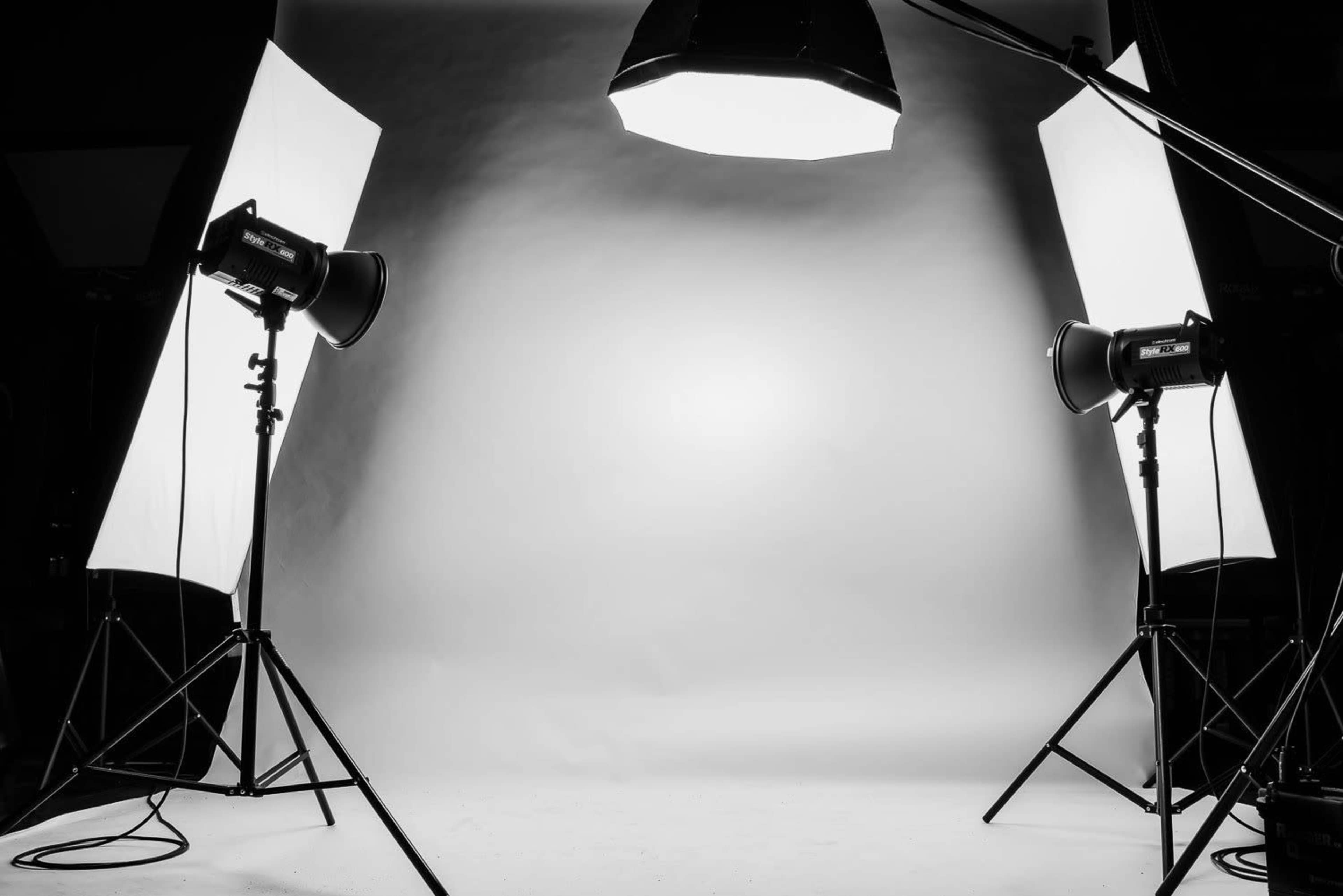 A photo studio setup with two softbox lights positioned on either side of a white backdrop.