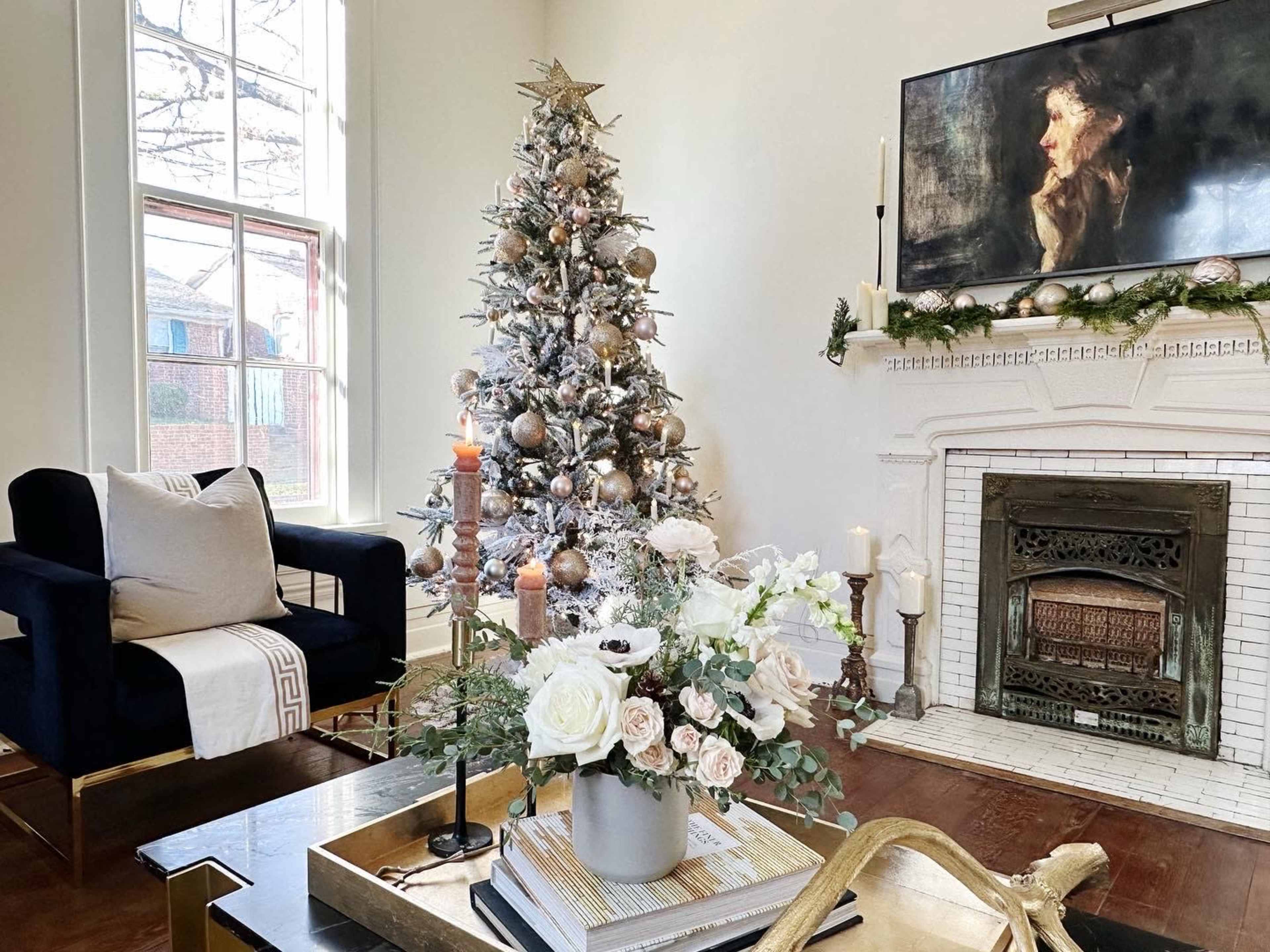 The image shows a decorated living room with a Christmas tree, a fireplace adorned with candles, and a stylish armchair beside a coffee table.