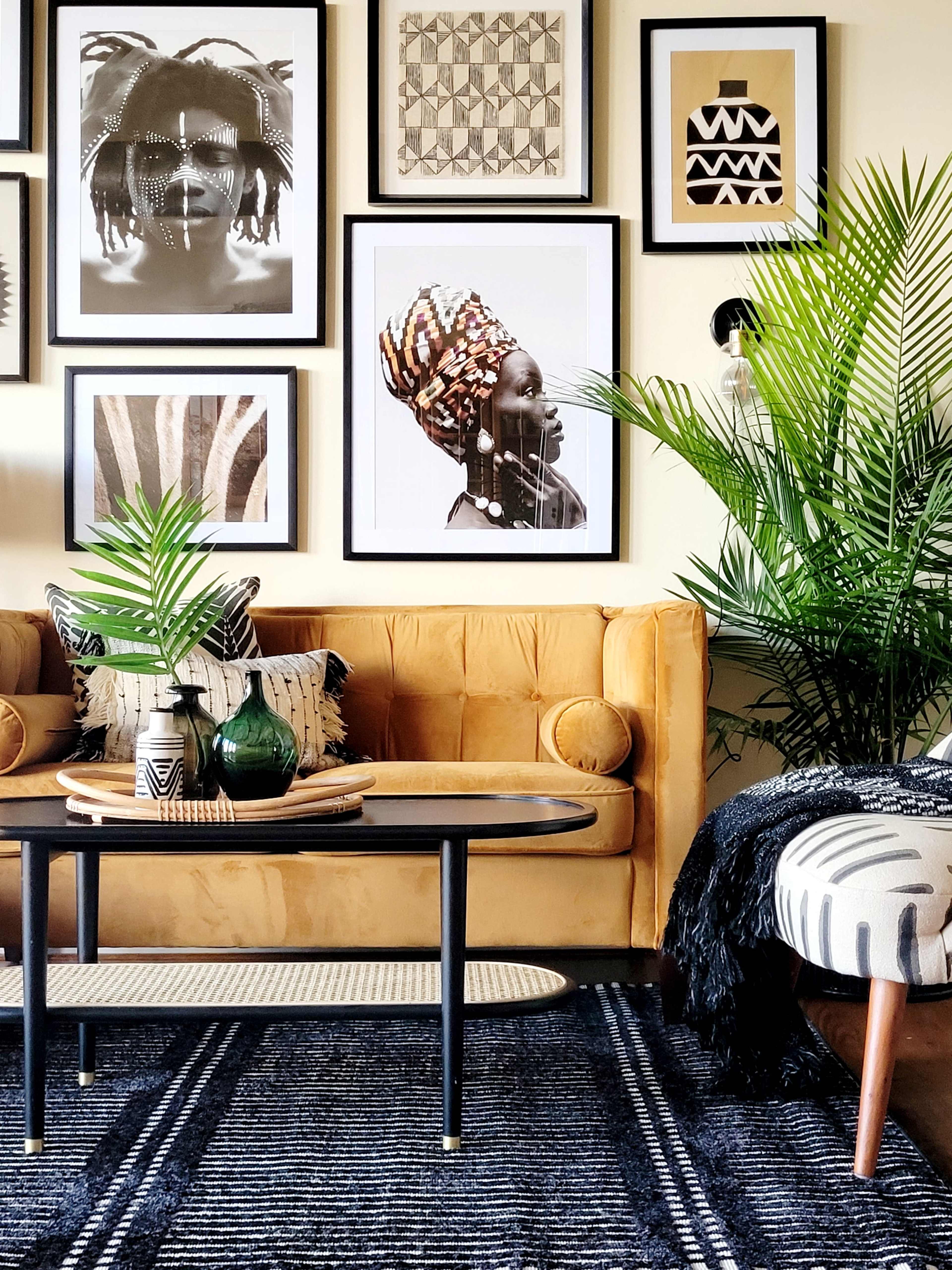 A mustard yellow sofa is positioned in a room adorned with framed artwork and greenery, creating a stylish and inviting interior.