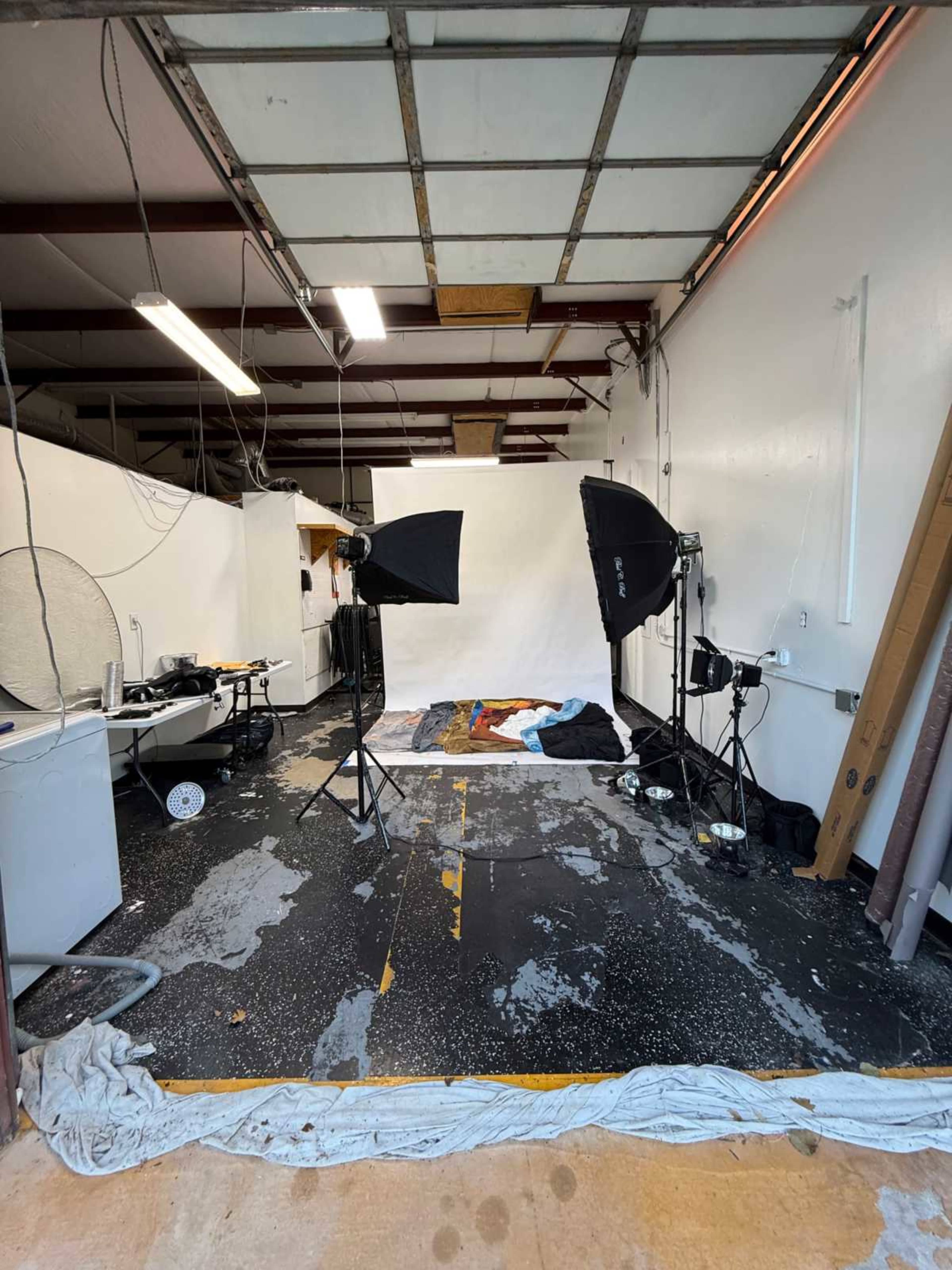 A photography studio with backdrop equipment, lights, and a partially messy floor is shown.