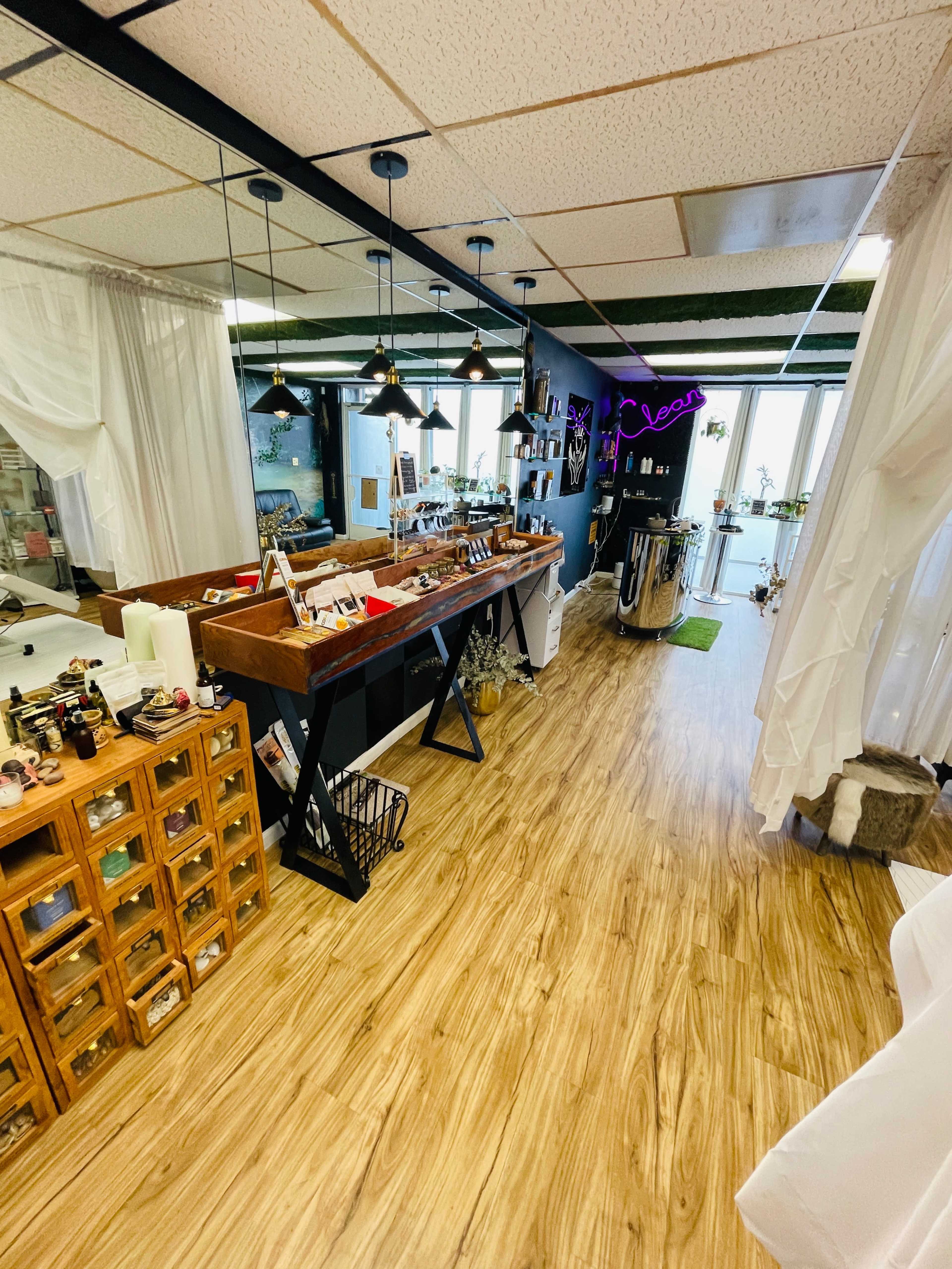 The image shows a bright interior of a boutique with wooden flooring, a display counter on the left side, and various decorative items along the walls.