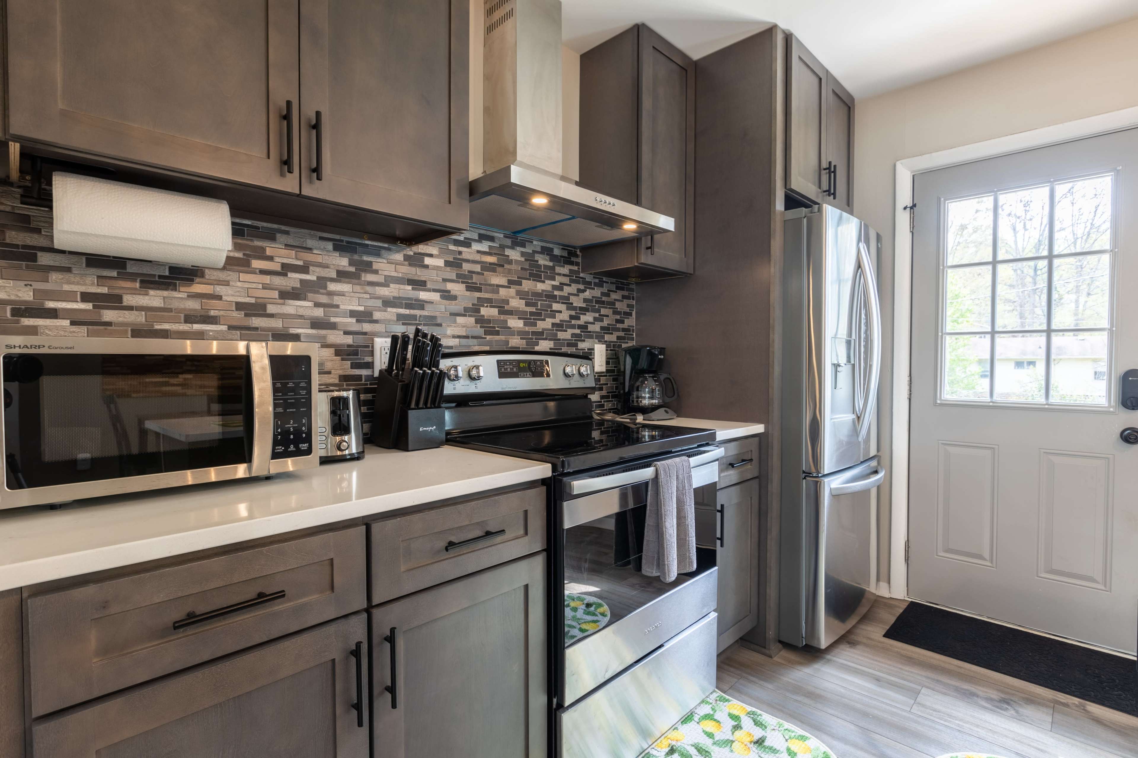 A modern kitchen featuring stainless steel appliances, gray cabinetry, and a door leading to the outside.