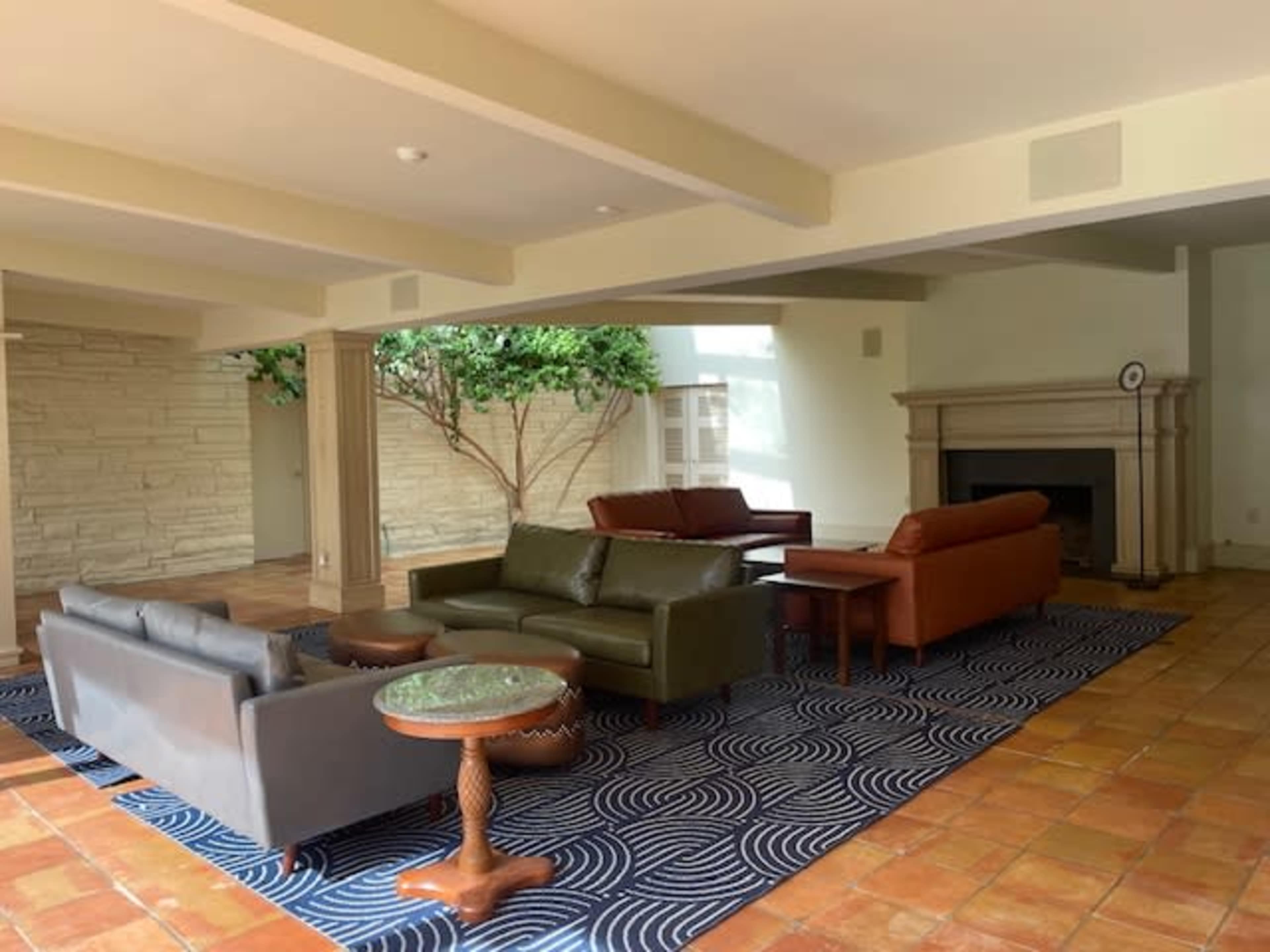 A spacious living area with multiple sofas, a coffee table, and a fireplace, surrounded by stone walls and a large window.