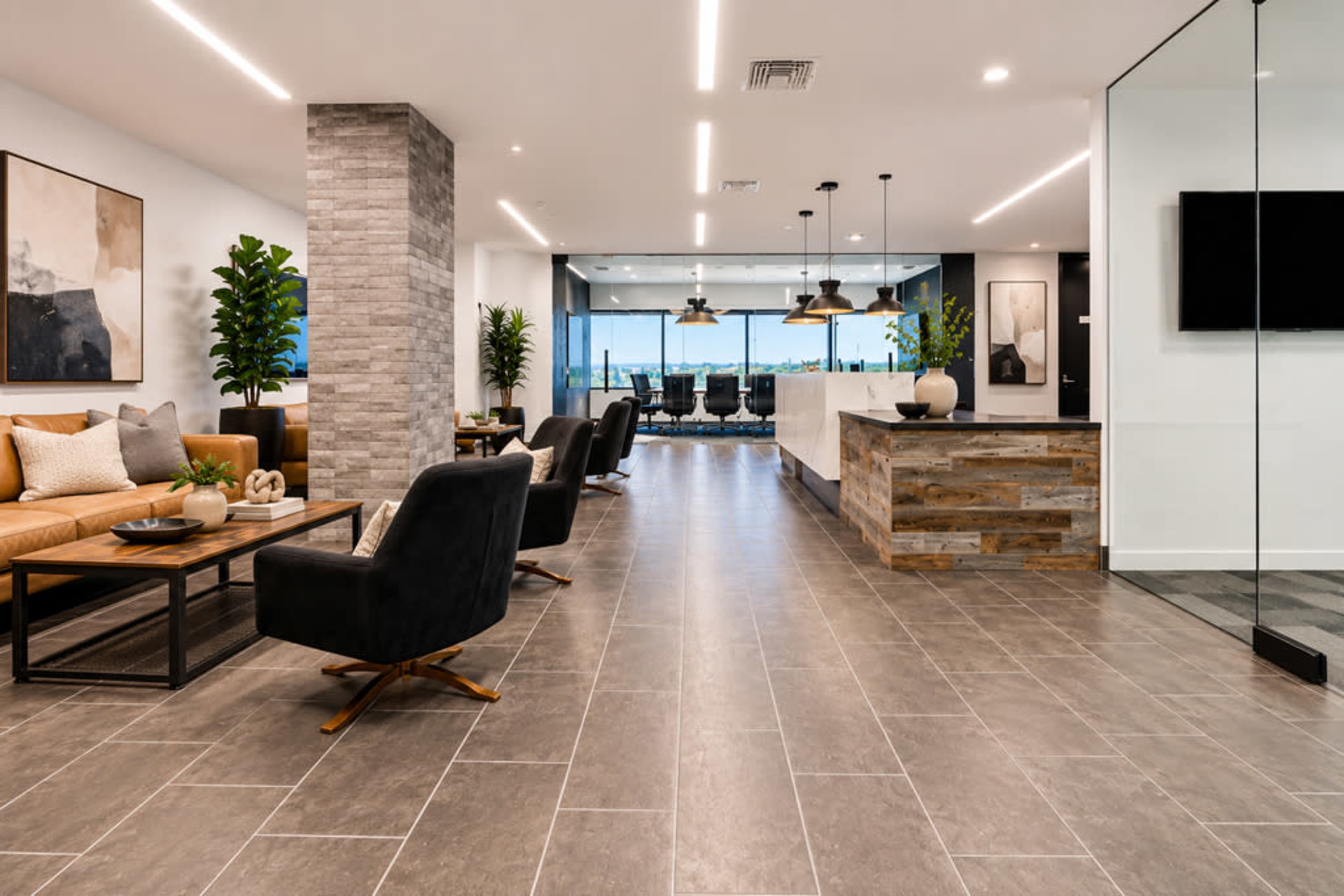 The image shows a modern lobby area featuring a mix of seating arrangements, large windows with a view, and contemporary decor elements.