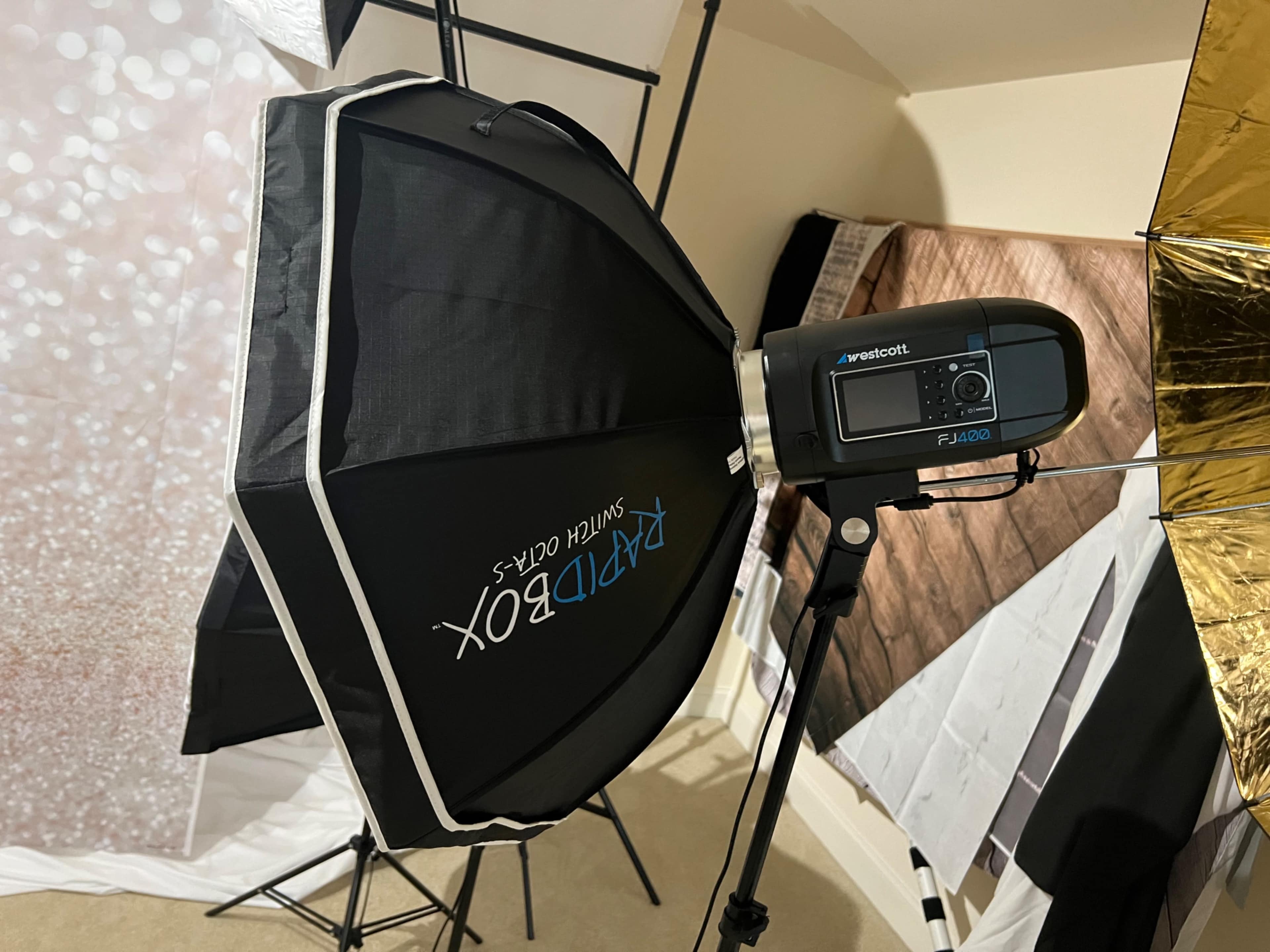 A photography studio setup featuring a softbox light and a flash unit.