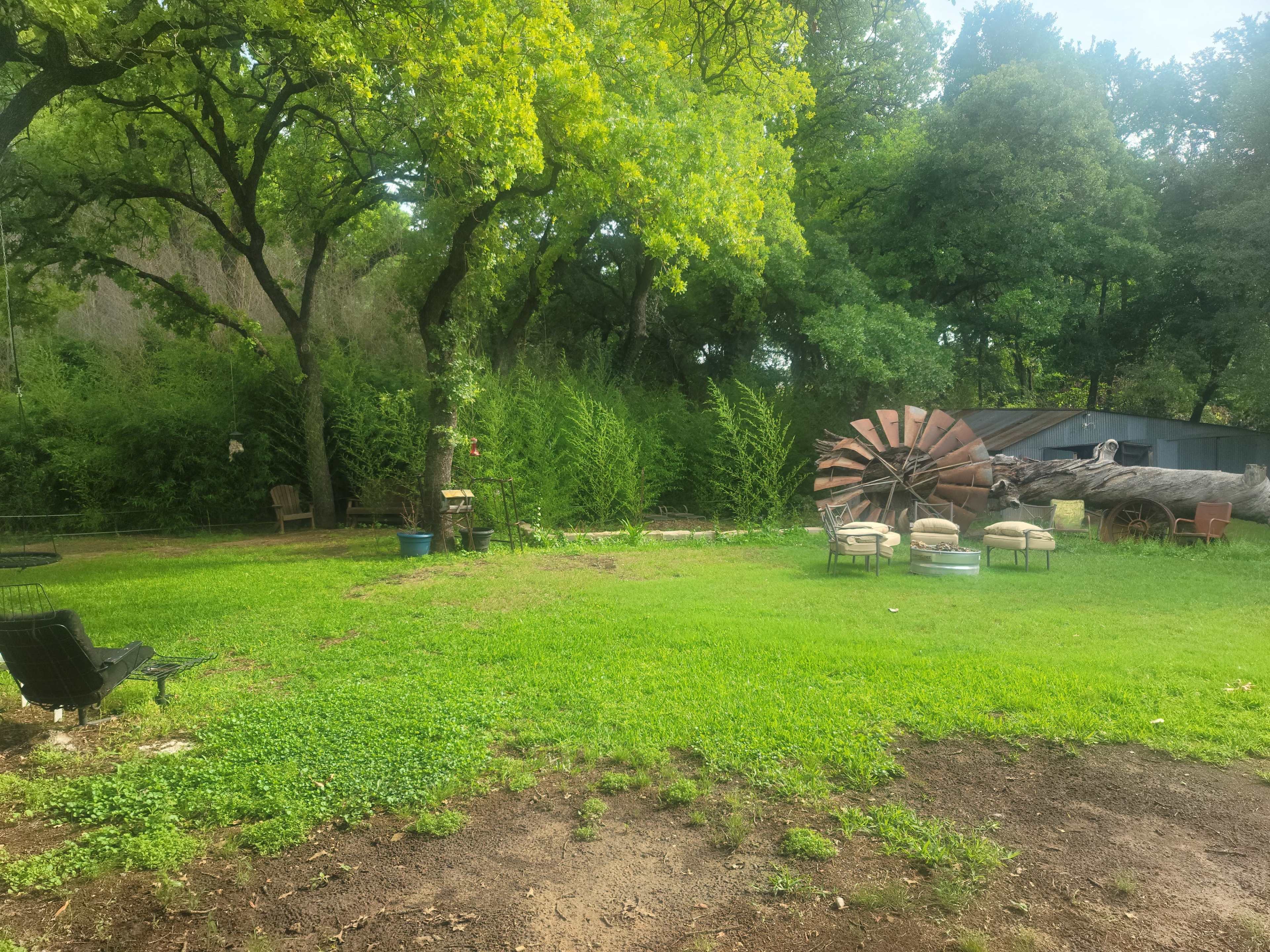 A grassy outdoor area with trees, garden chairs, and a large windmill in the background.