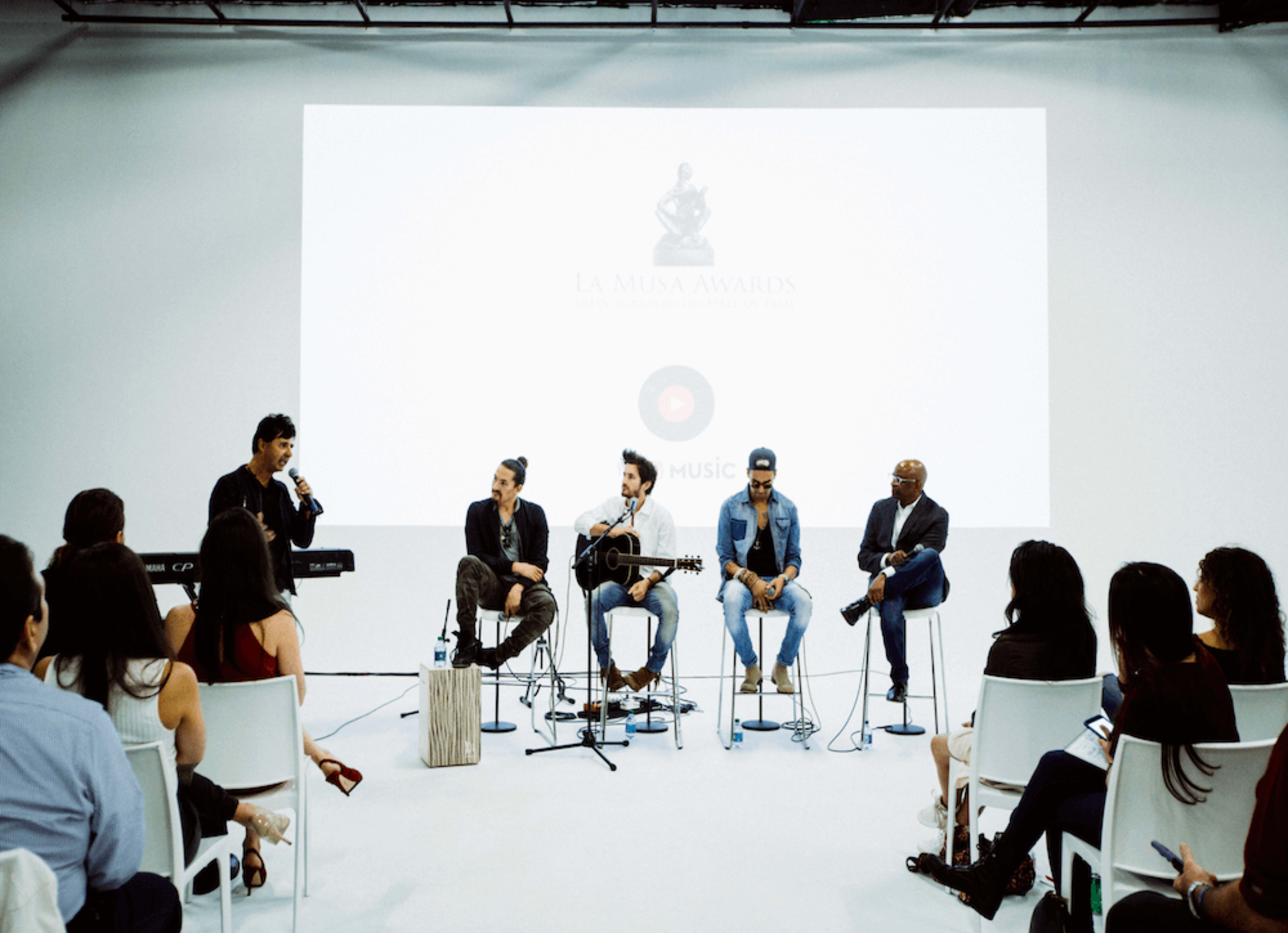 A panel of musicians discusses their work in front of an audience at the La Musa Awards event.