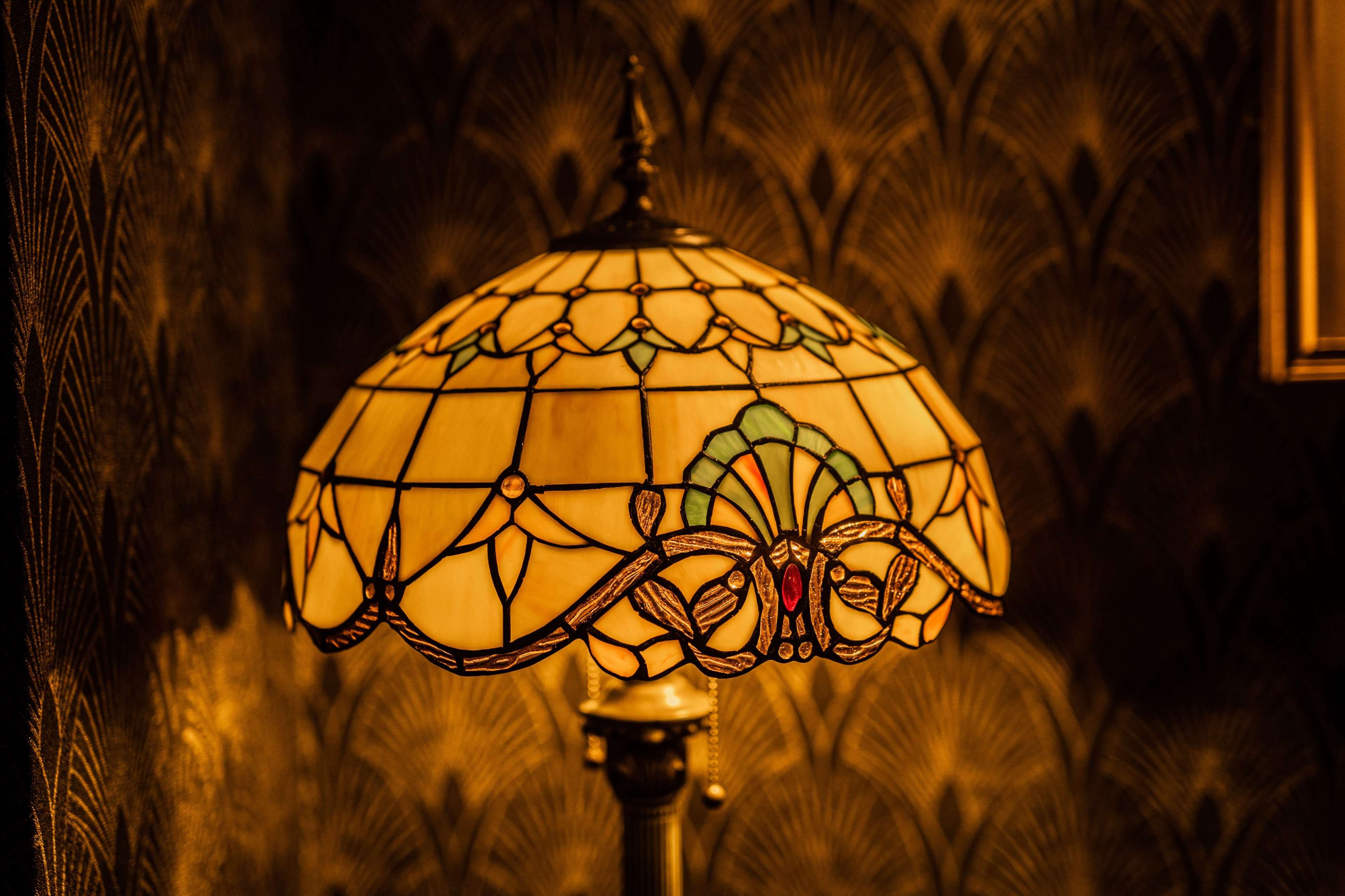 A stained glass lamp with a decorative shade featuring intricate patterns and colors.