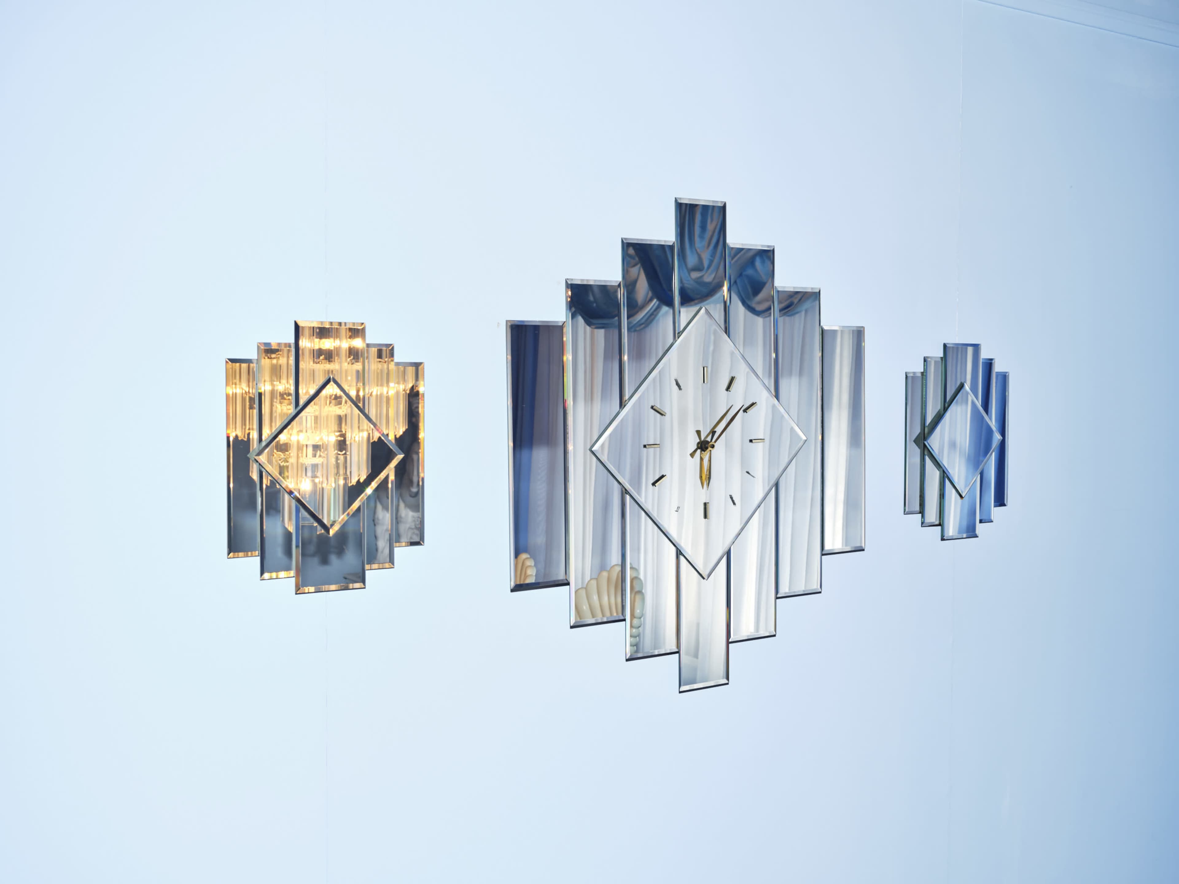 Three decorative wall clocks with geometric designs mounted on a white wall.