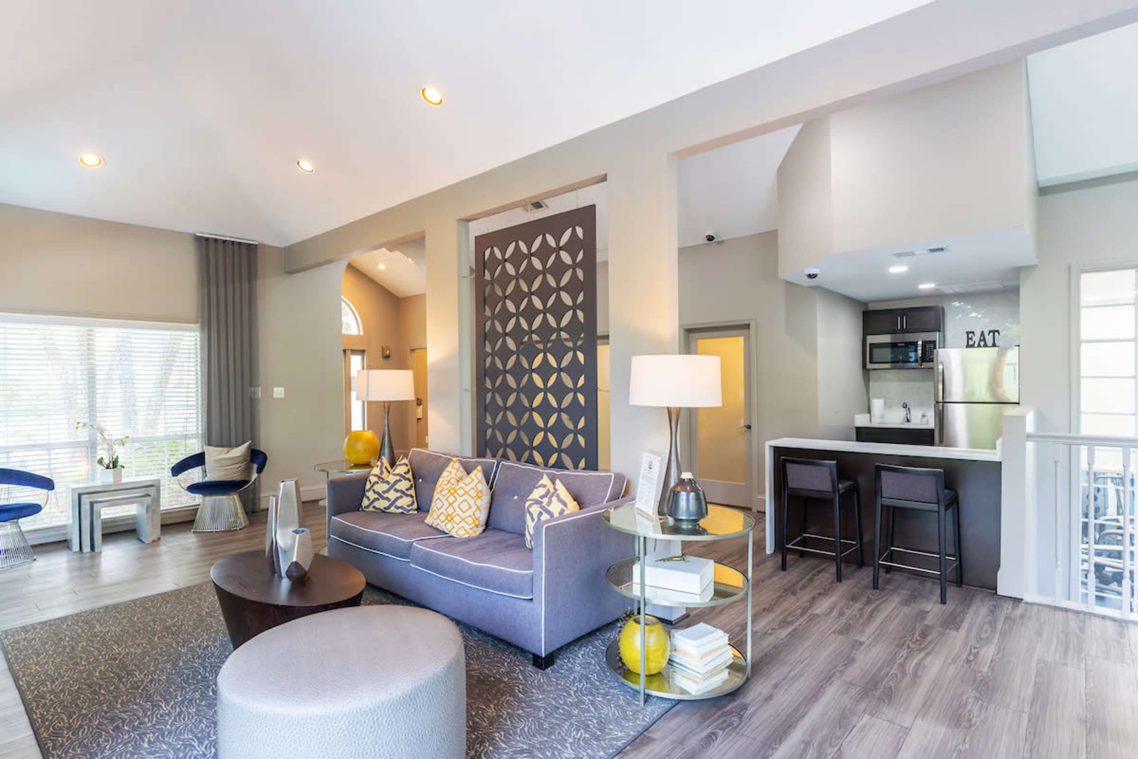 A modern living area with a sofa, a round coffee table, and a kitchen in the background.