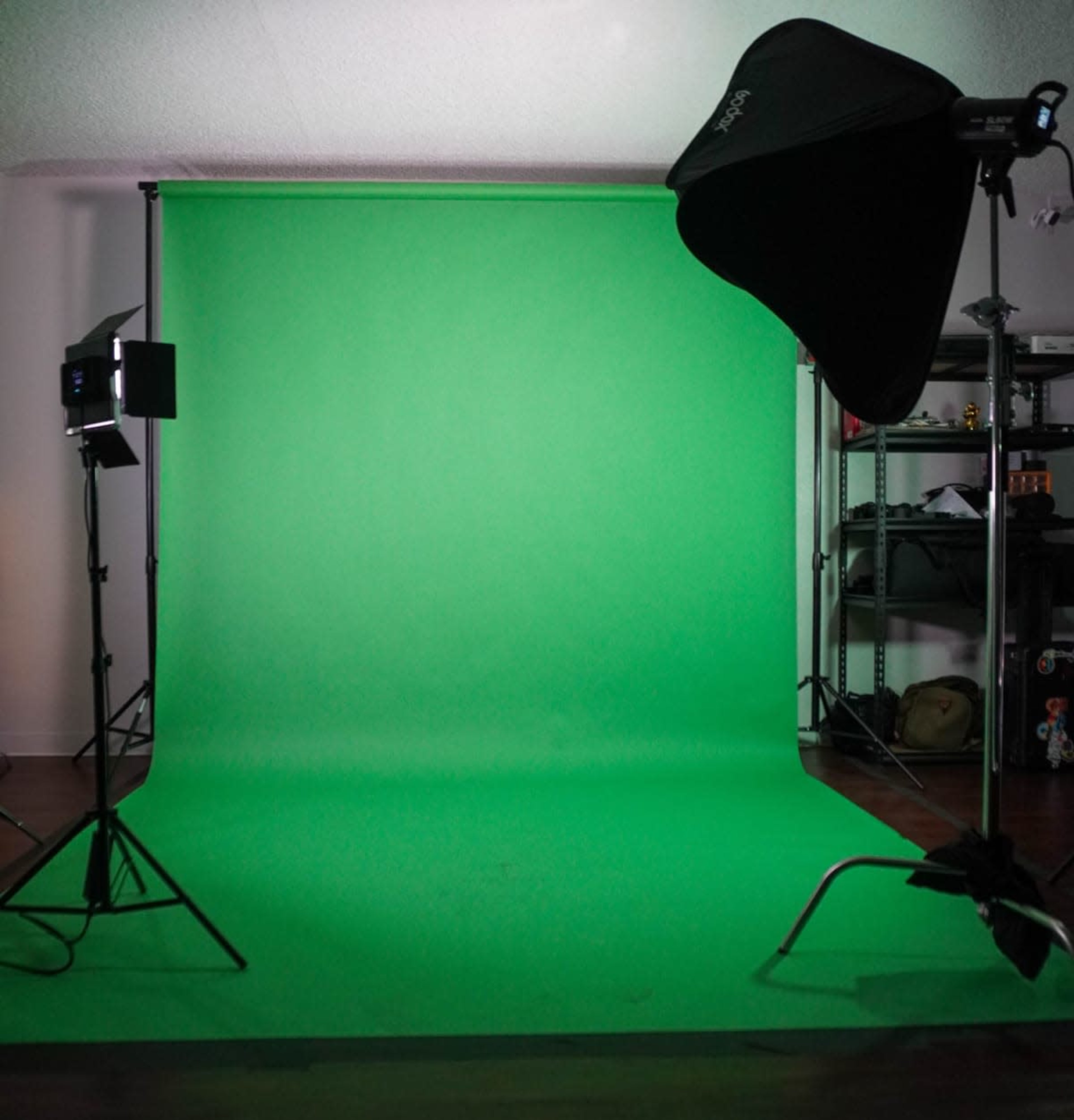 The image shows a photography studio setup featuring a green backdrop, lighting equipment, and various props on shelves in the background.