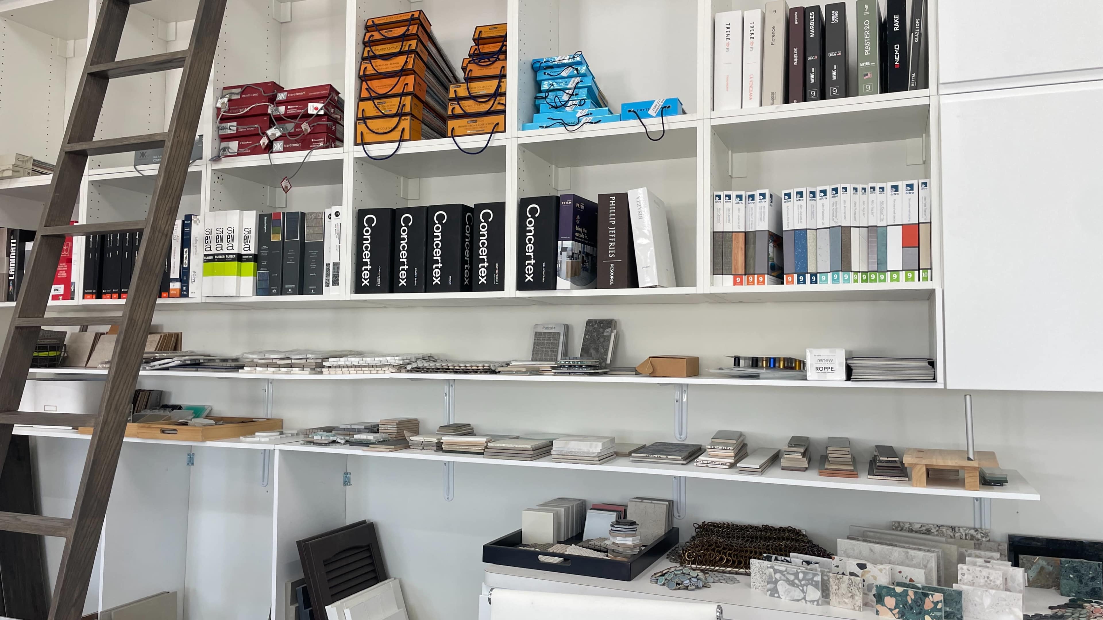 A neat display of various samples and materials organized on shelves, including binders, tiles, and design samples.