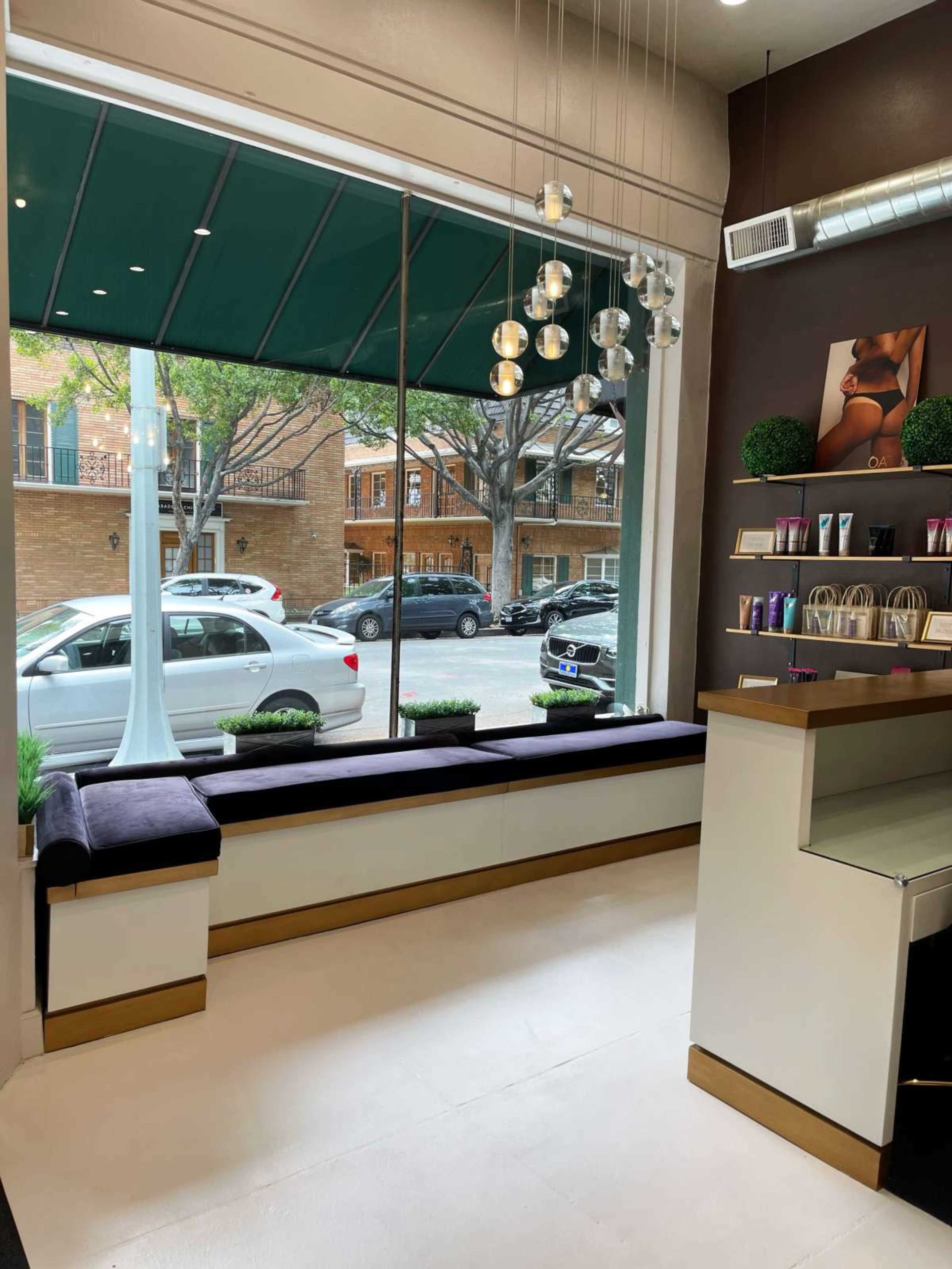 The image shows the interior of a modern storefront featuring a window with a view of a street and seating along the window ledge.