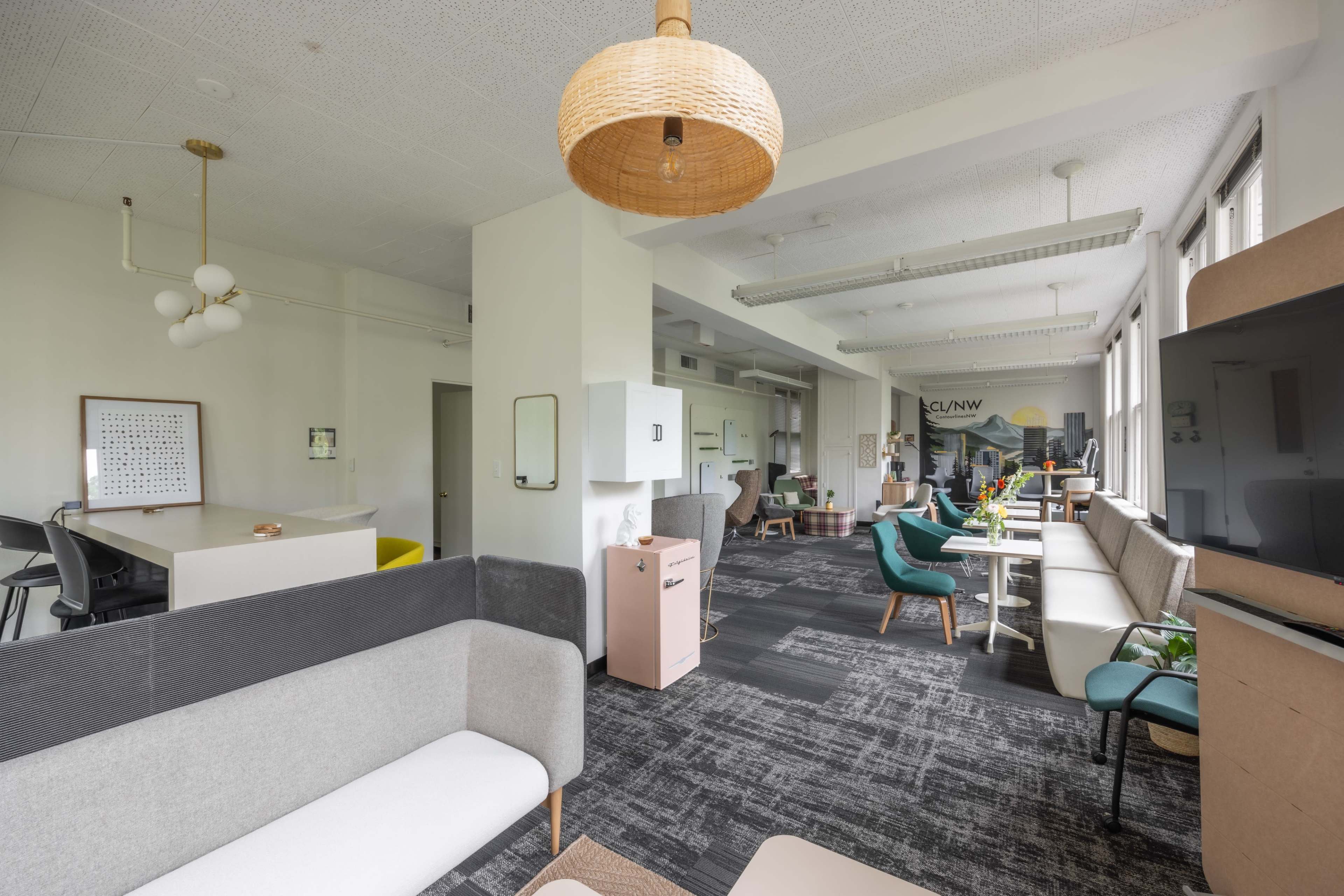 A modern office space with a mix of seating arrangements, workstations, and decorative elements.