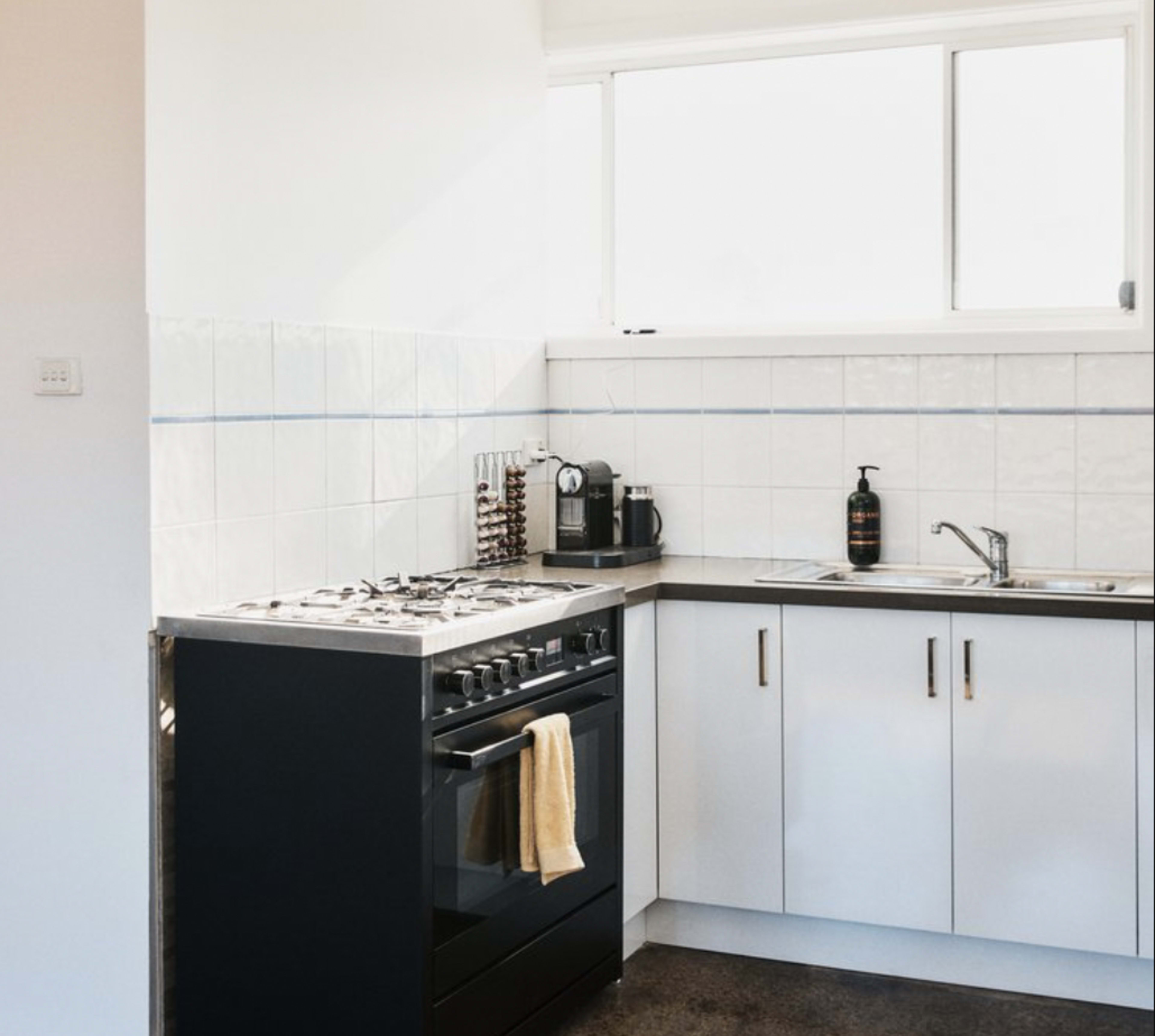 A modern kitchen with a gas stove, stainless steel appliances, and white cabinetry.