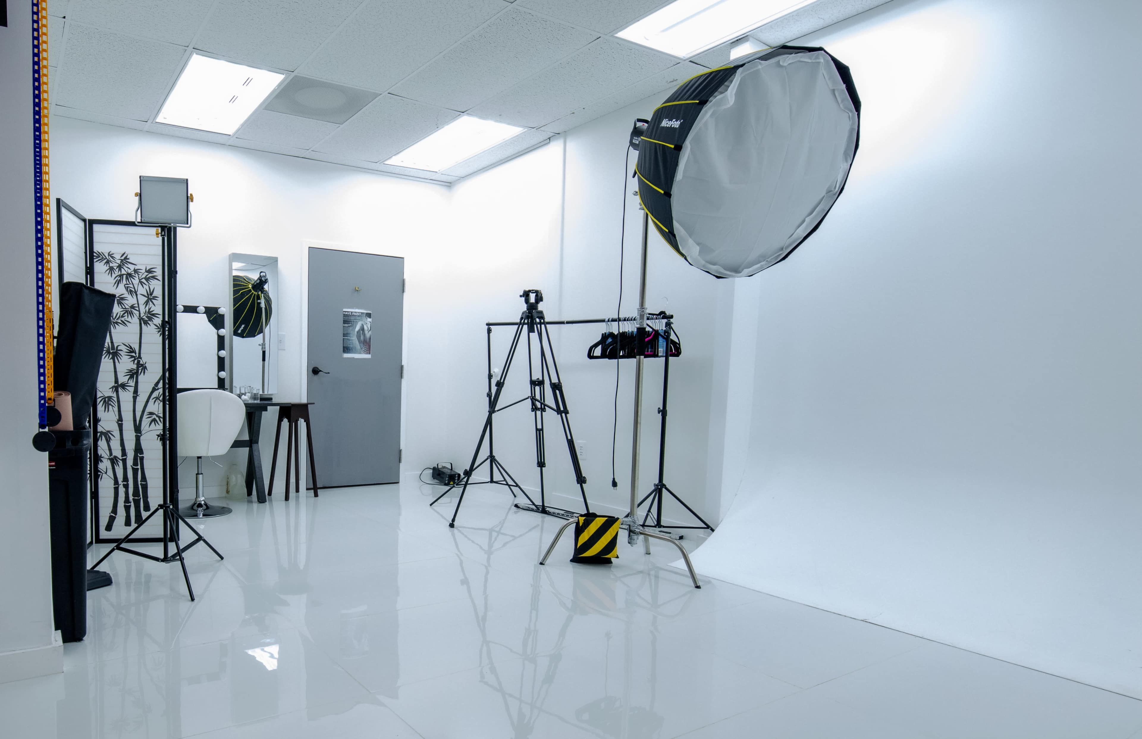 A photography studio equipped with a backdrop, lighting apparatus, and various stands and tools.