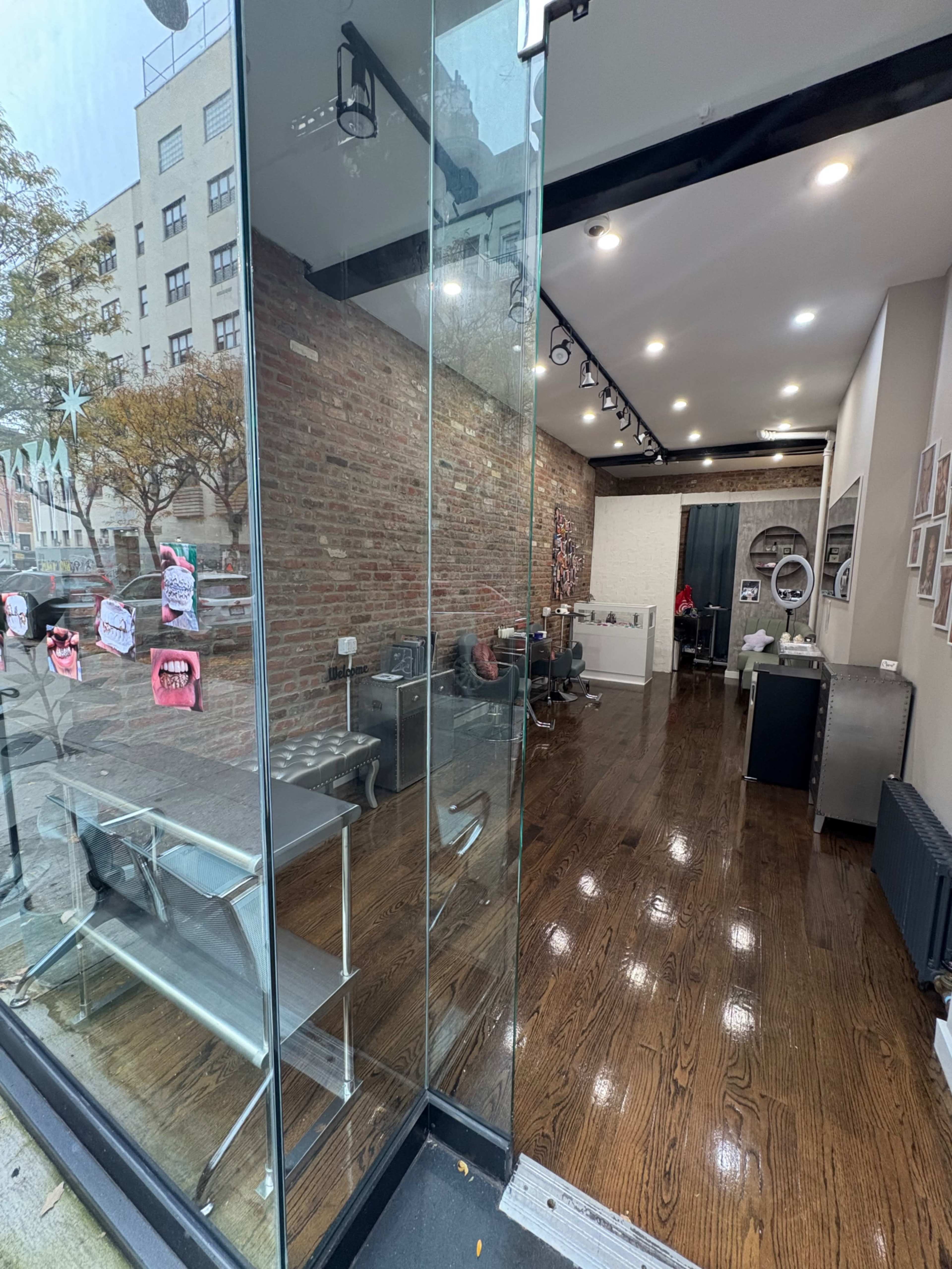 The image shows the entrance of a modern hair salon with large glass windows, wooden floors, and minimalist interior furniture.