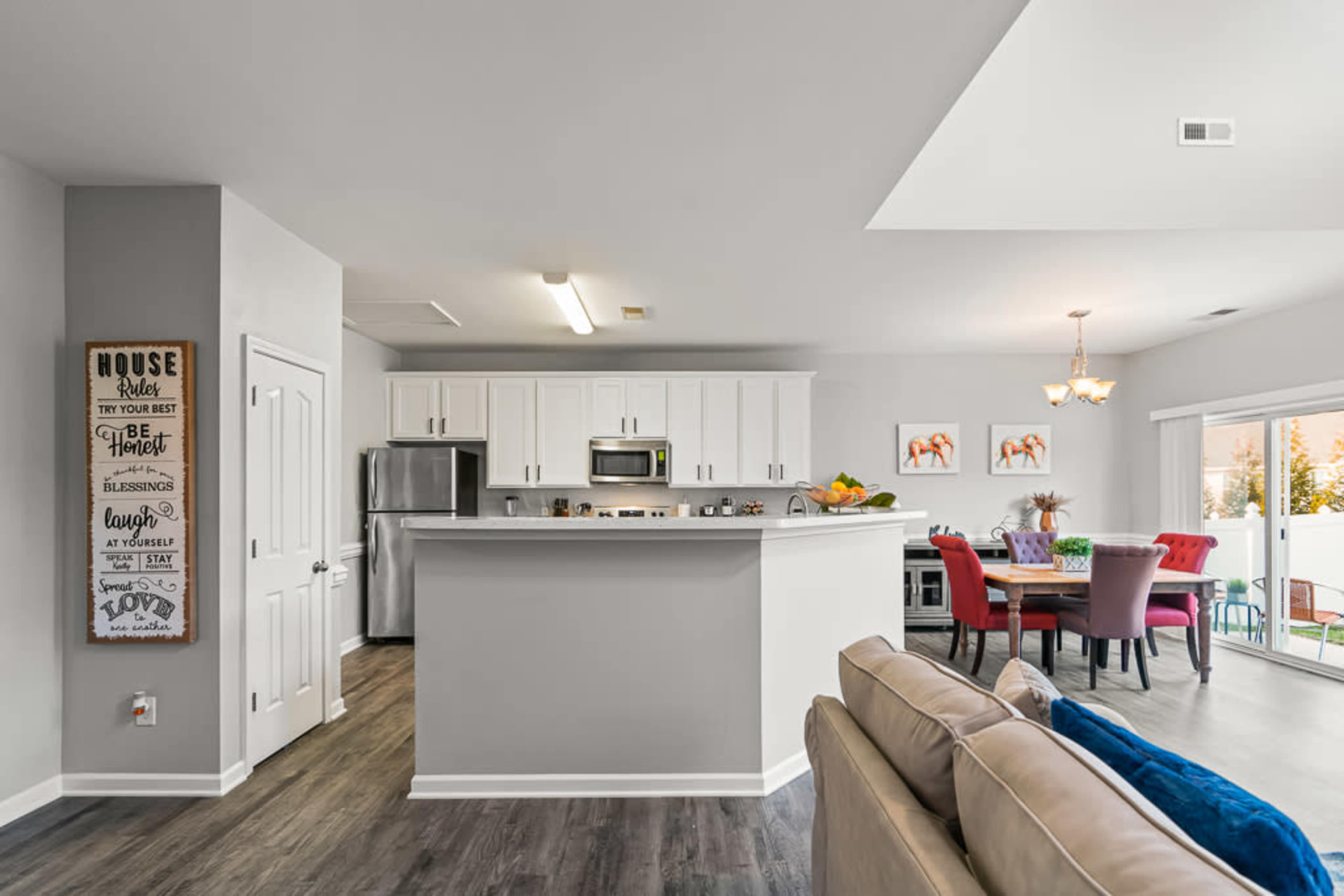 A modern kitchen with white cabinets and stainless steel appliances opens up to a dining area featuring a colorful table and chairs.
