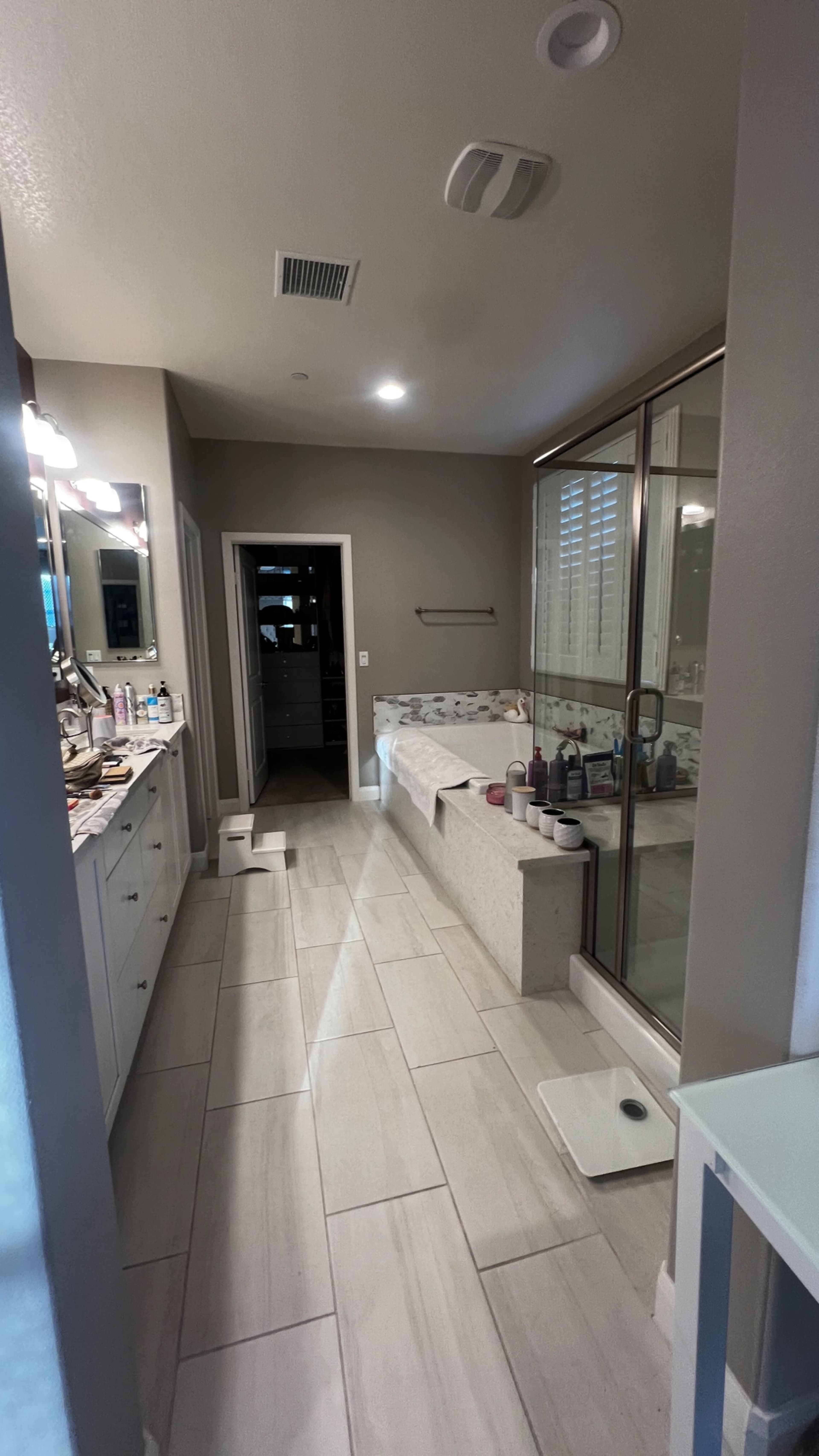 A modern bathroom featuring a double vanity, a glass shower enclosure, and a freestanding bathtub along a tiled floor.