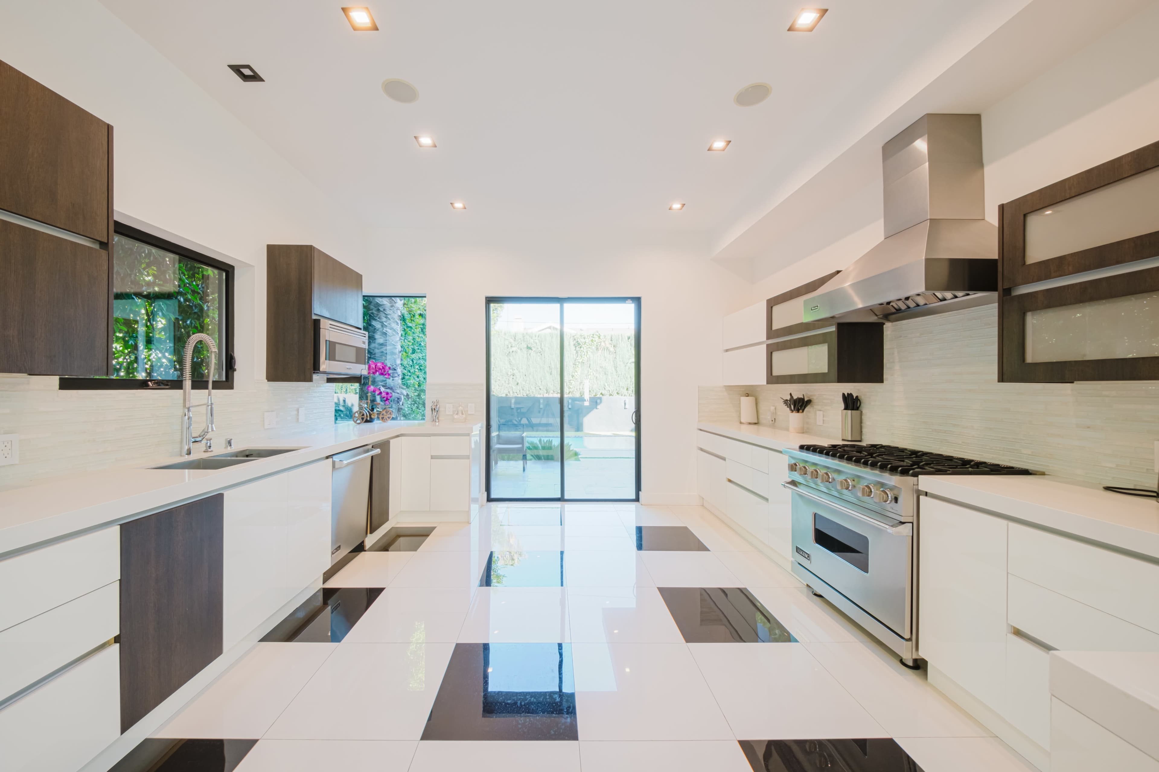 The image features a modern kitchen with white cabinets, a stainless steel stove, and a sliding glass door leading to an outdoor area.