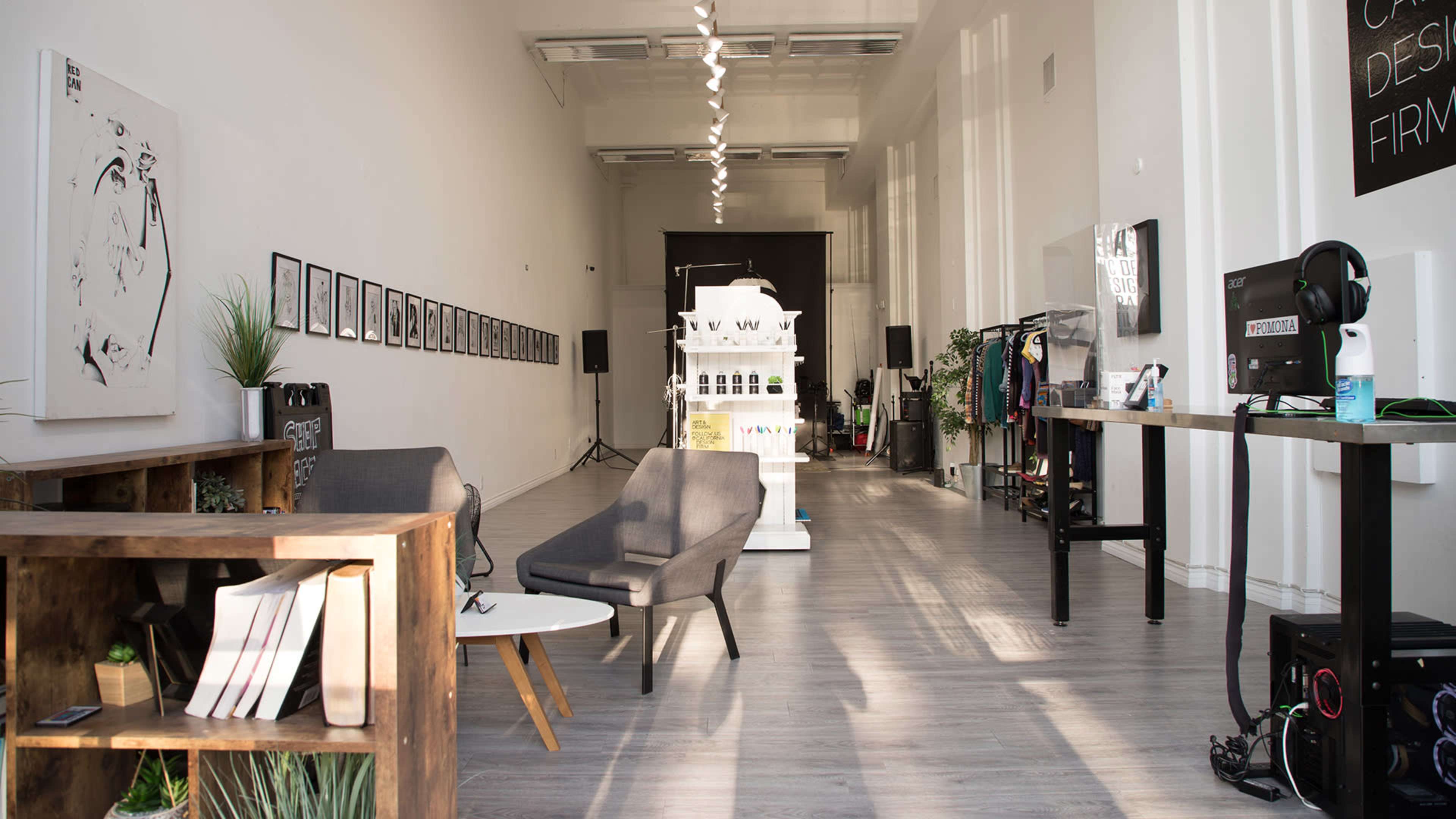 A spacious interior of a design studio featuring modern furniture, framed artwork on the walls, and display areas for products.